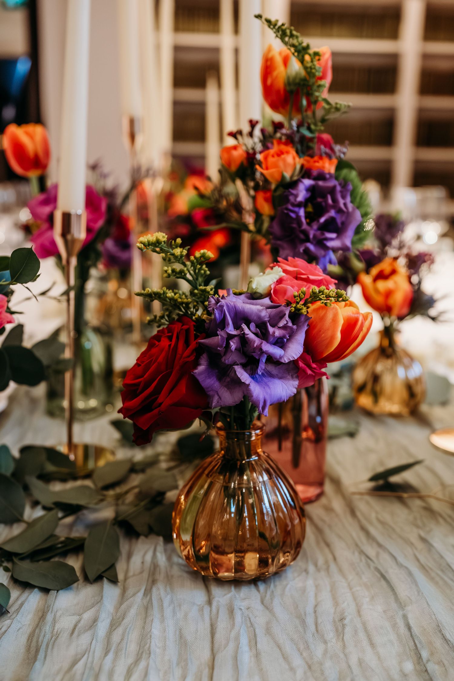 Vibrant floral arrangement with purple and orange blooms in an amber glass vase.
