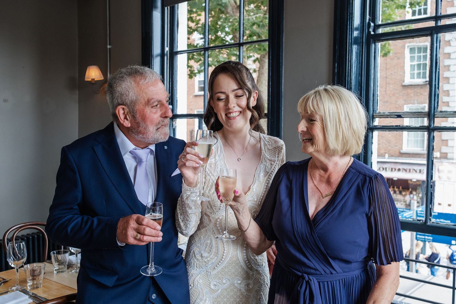 Wedding celebration at a restaurant with guests enjoying drinks by a window.