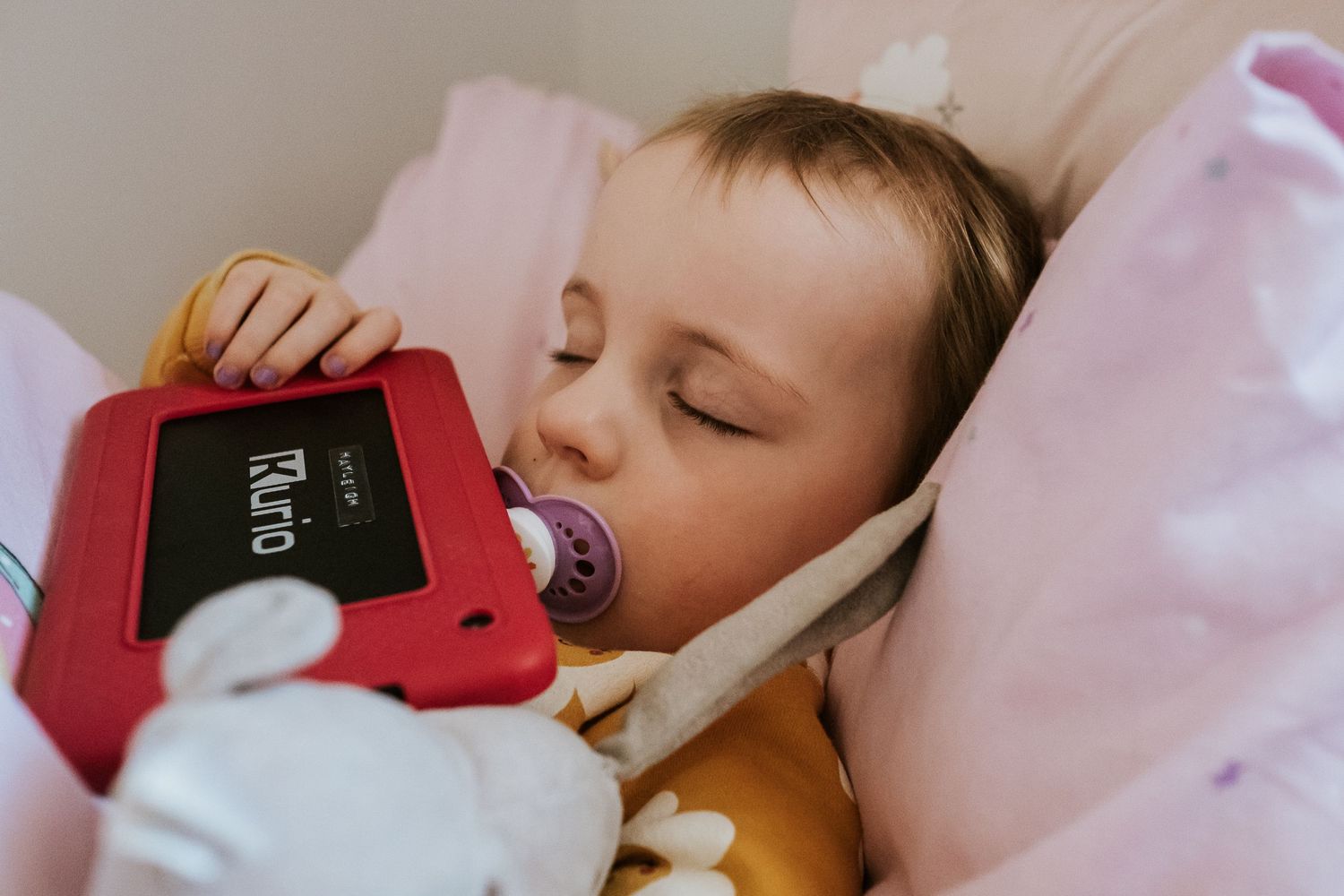 Peaceful naptime scene with toy and pacifier on pink bedding.