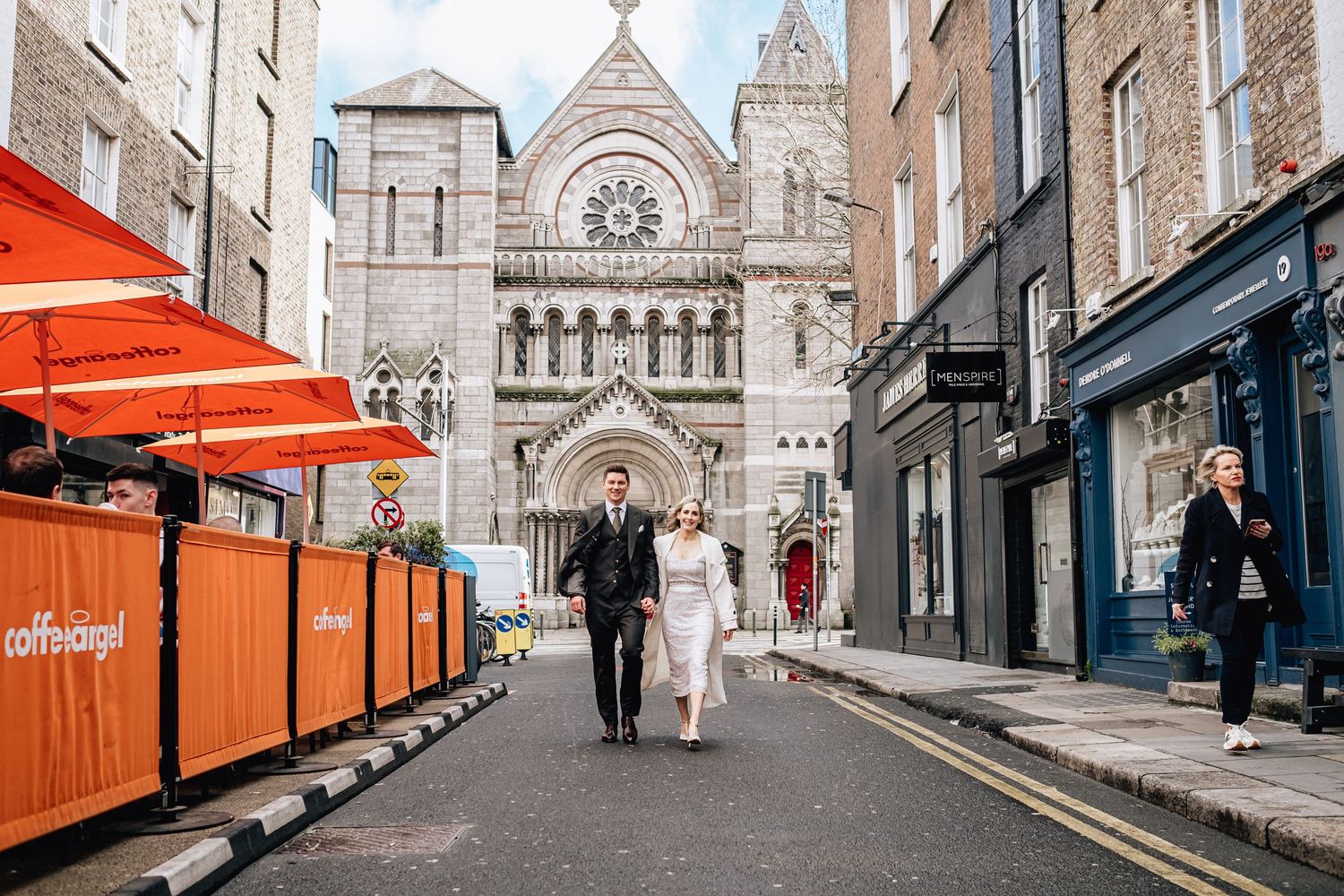 Couple walks towards historic church entrance with orange street barriers visible.