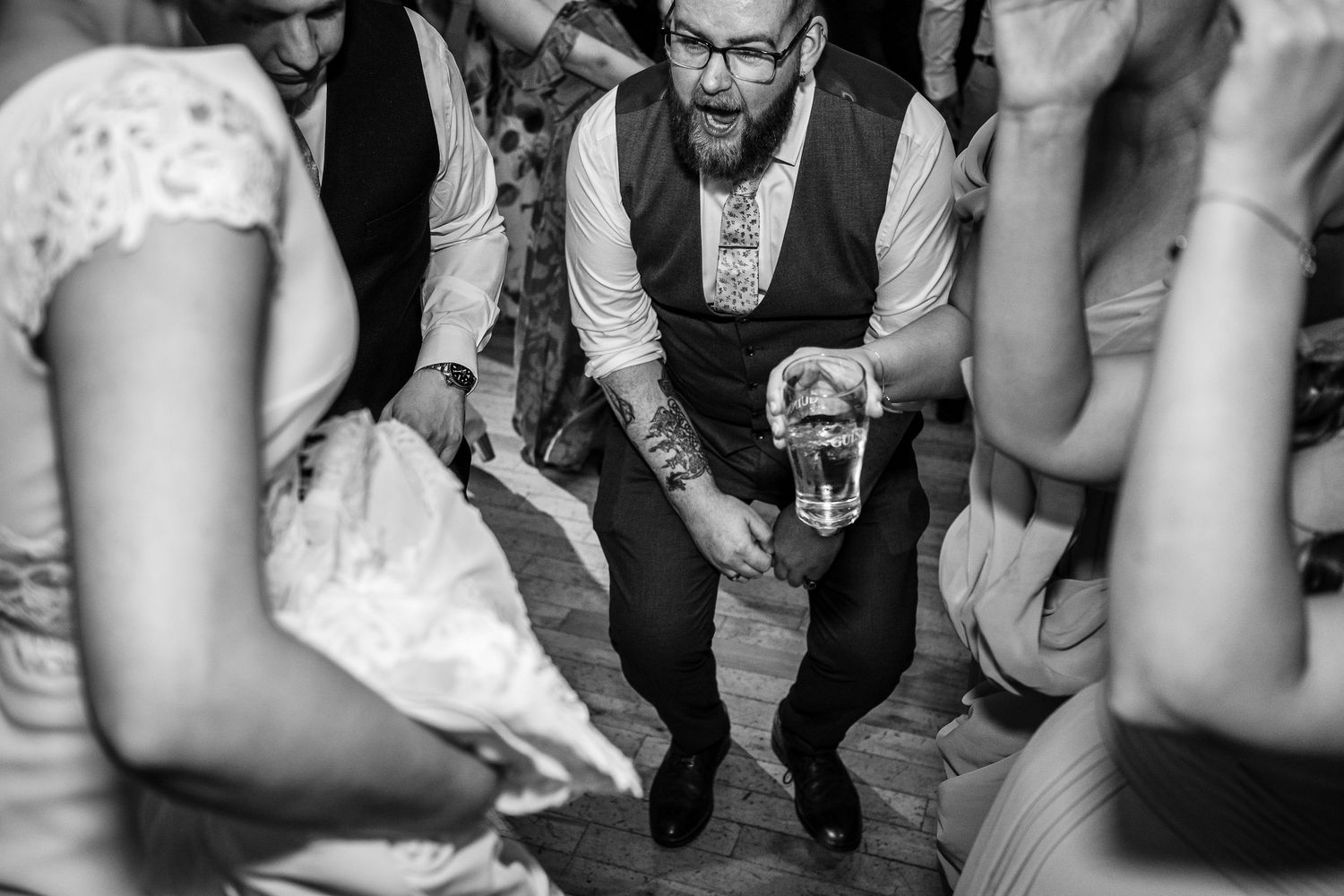 Black and white shot of wedding reception dance floor with party guests celebrating.