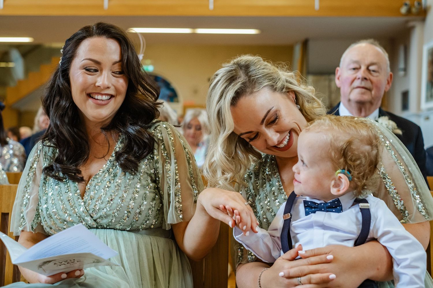 Joyful laughter shared during a wedding ceremony with a small child in formal wear.