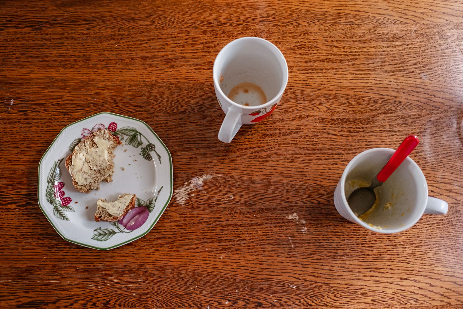 Empty coffee cups and a decorative plate sit on a wooden table surface.
