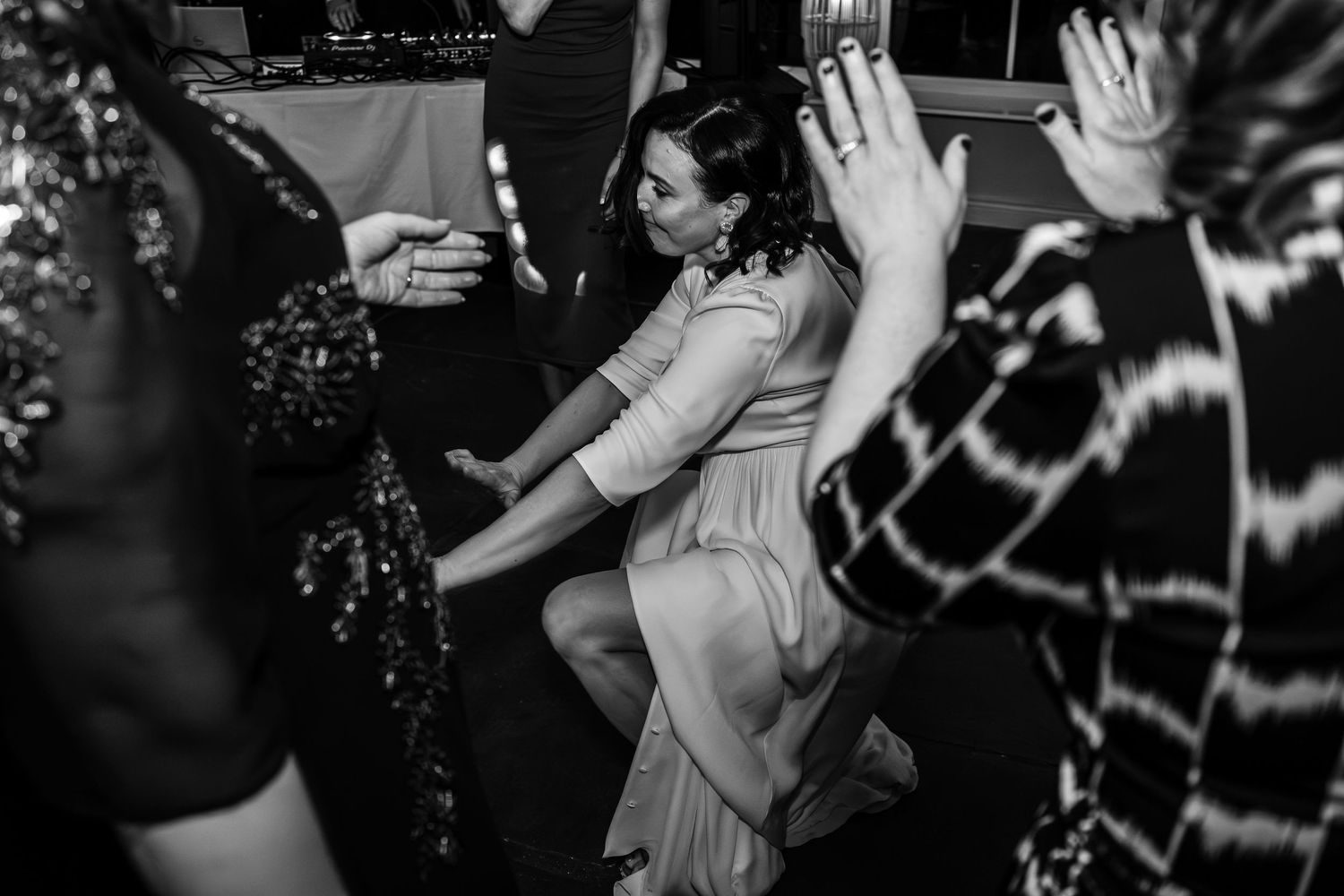 Black and white photo of a wedding guest dancing energetically on the dance floor during a reception.