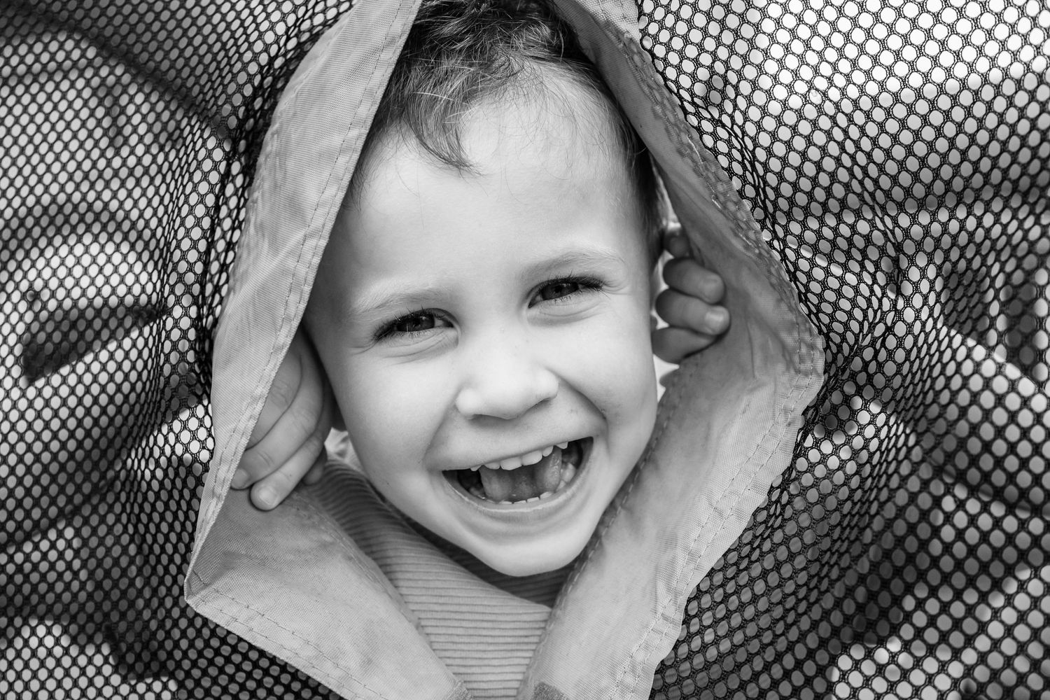 Joyful expression shown through a mesh opening in black and white.