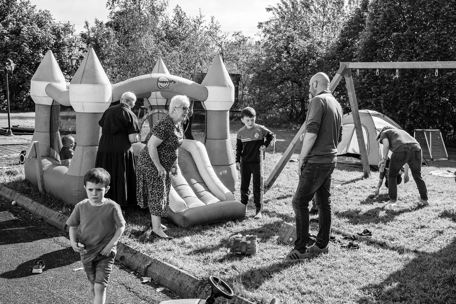 Black and white image of a backyard party with an inflatable bounce castle.