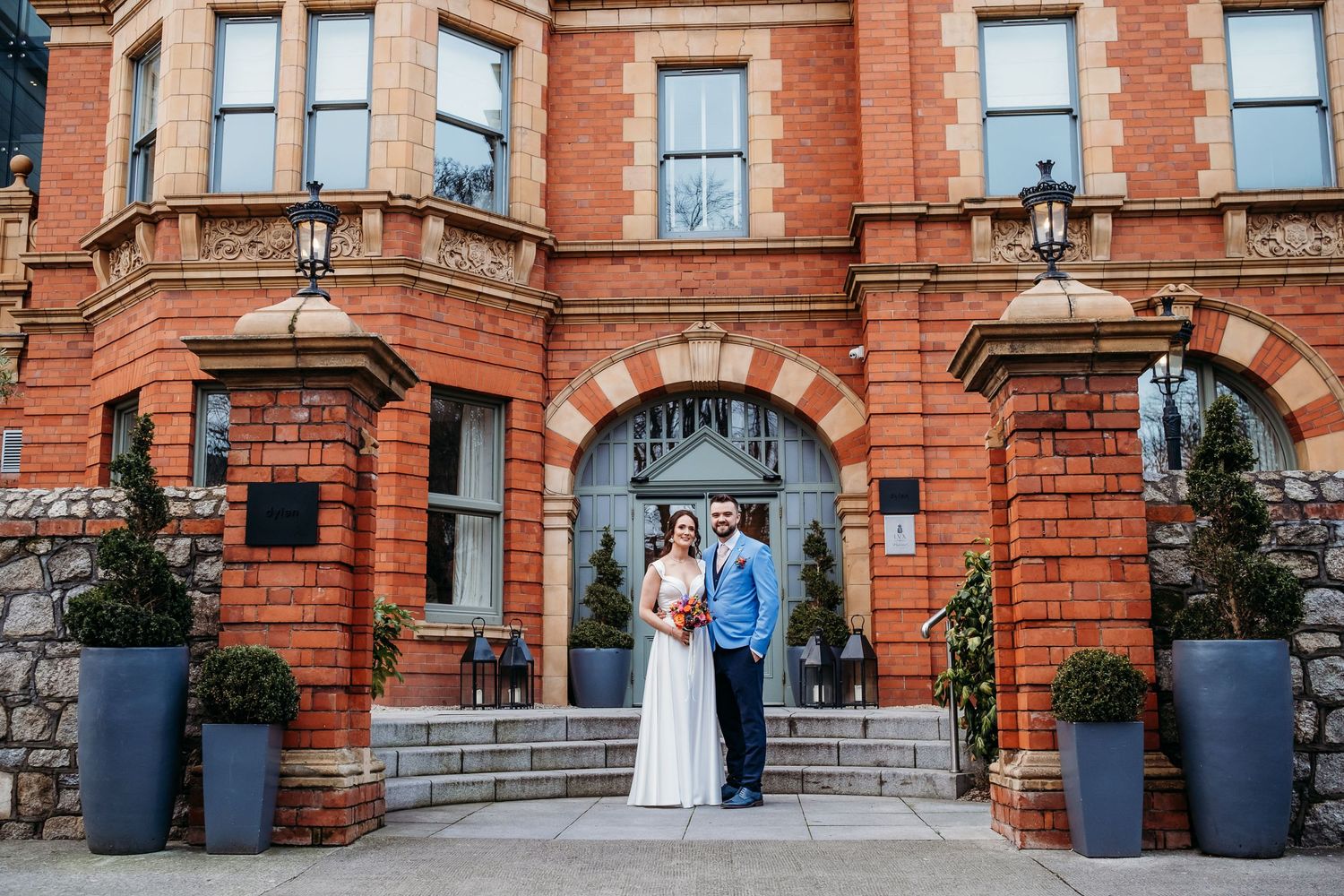 Historic red brick building entrance decorated with large blue planters.
