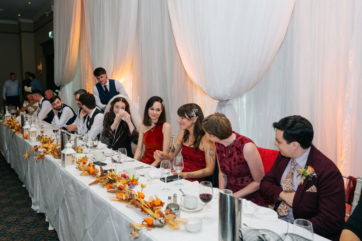 Wedding reception table decorated with autumn-themed centerpieces and white linens.