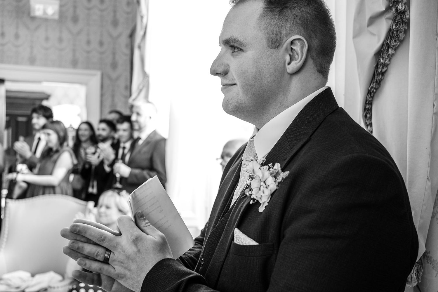 Black and white photo of a guest at a formal event with a boutonniere.