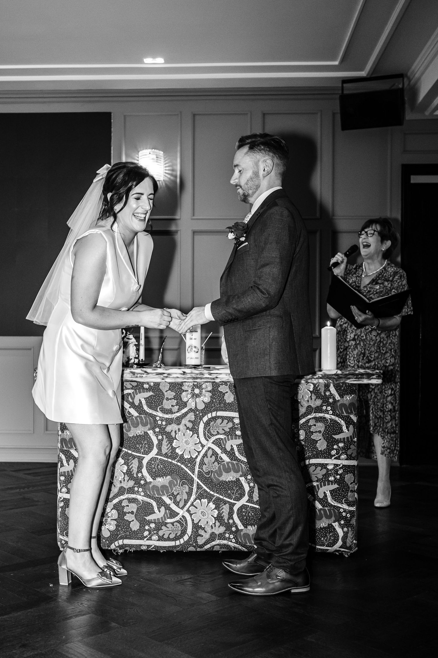 Wedding couple shares a joyful moment during reception beside a patterned table.