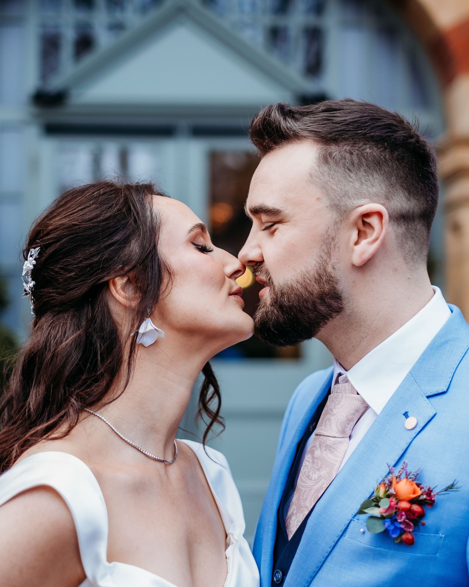 A romantic intimate moment between a couple on their wedding day against an outdoor backdrop.