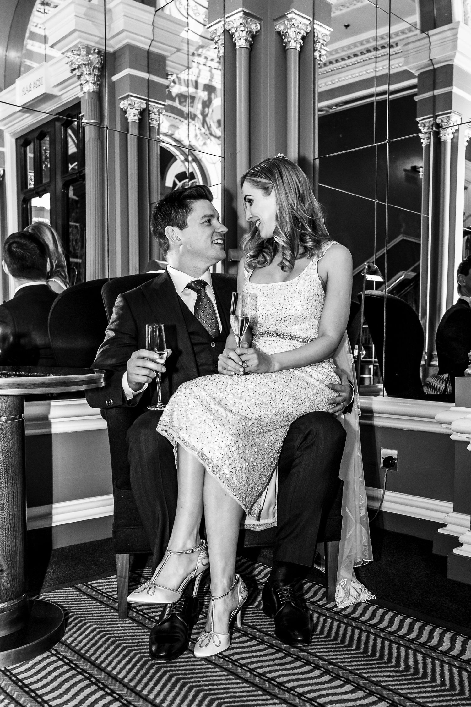 Romantic moment captured in black and white with elegant columns and mirrors in the background.