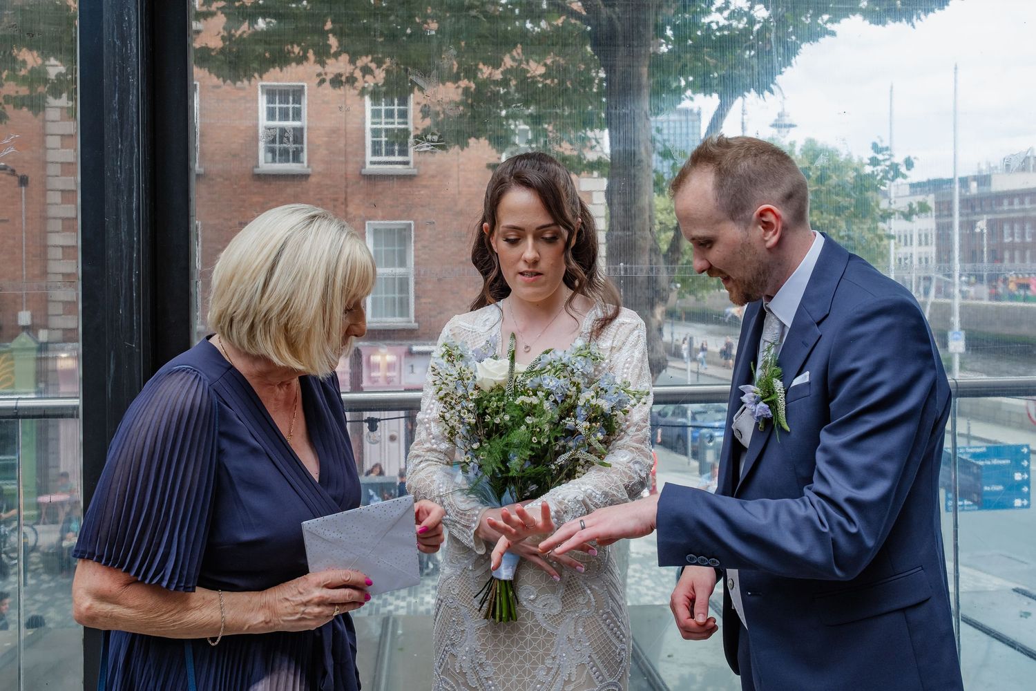 Intimate wedding ceremony in a building with large windows and natural light.
