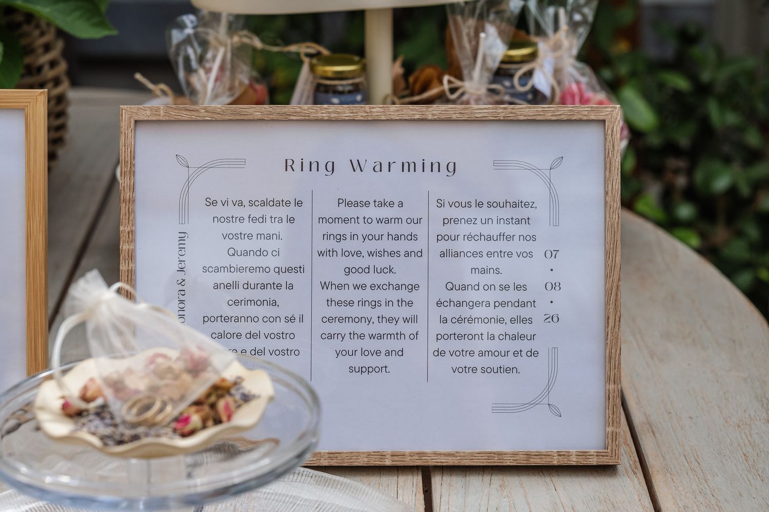 Ring warming ceremony sign displayed at a wedding reception with bilingual instructions in a rustic wooden frame.