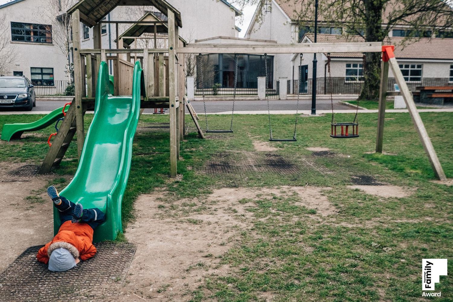 A panoramic view of a playground area with green slides and equipment in an outdoor setting.