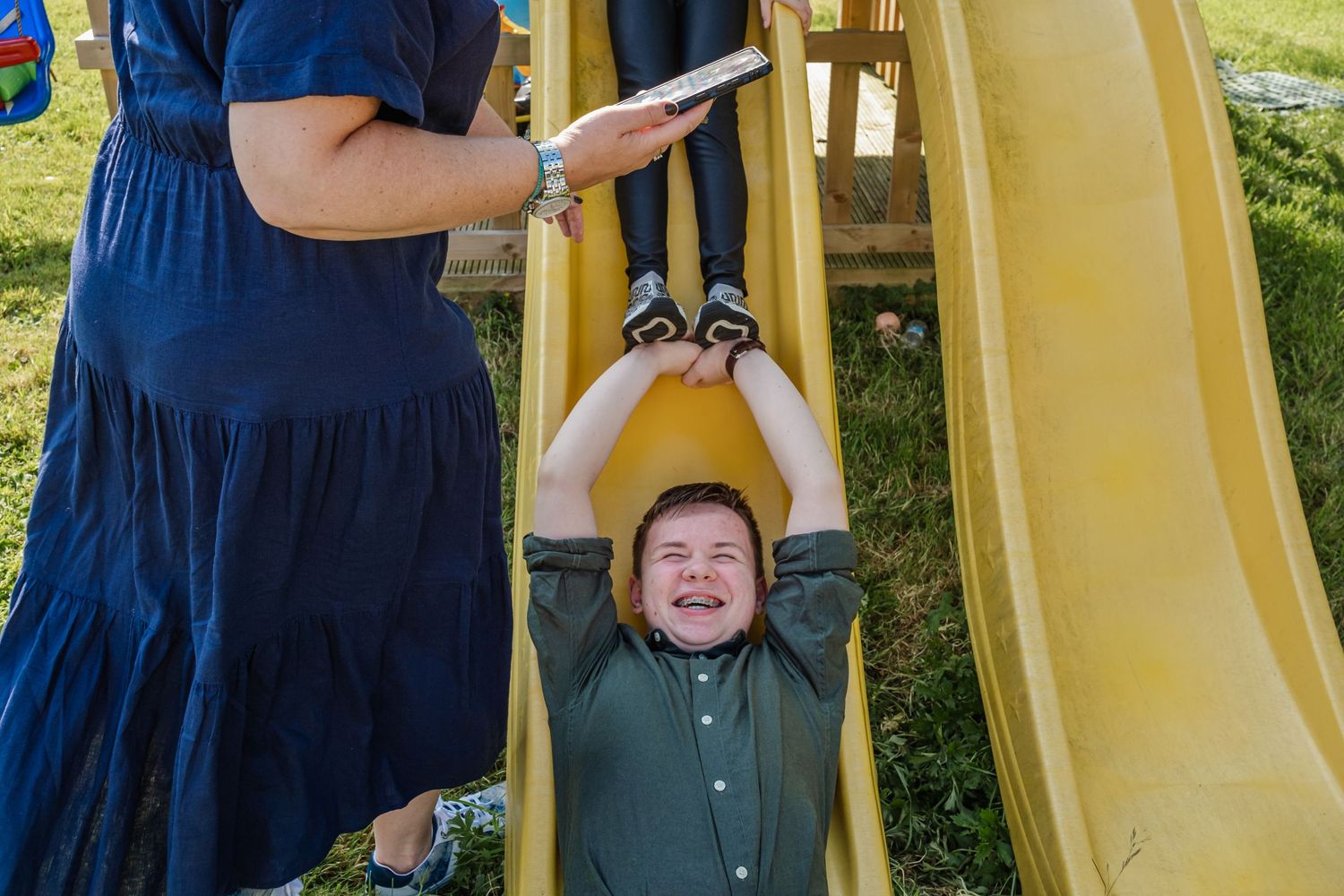 A playful moment at an outdoor playground with a yellow slide and navy blue dress.