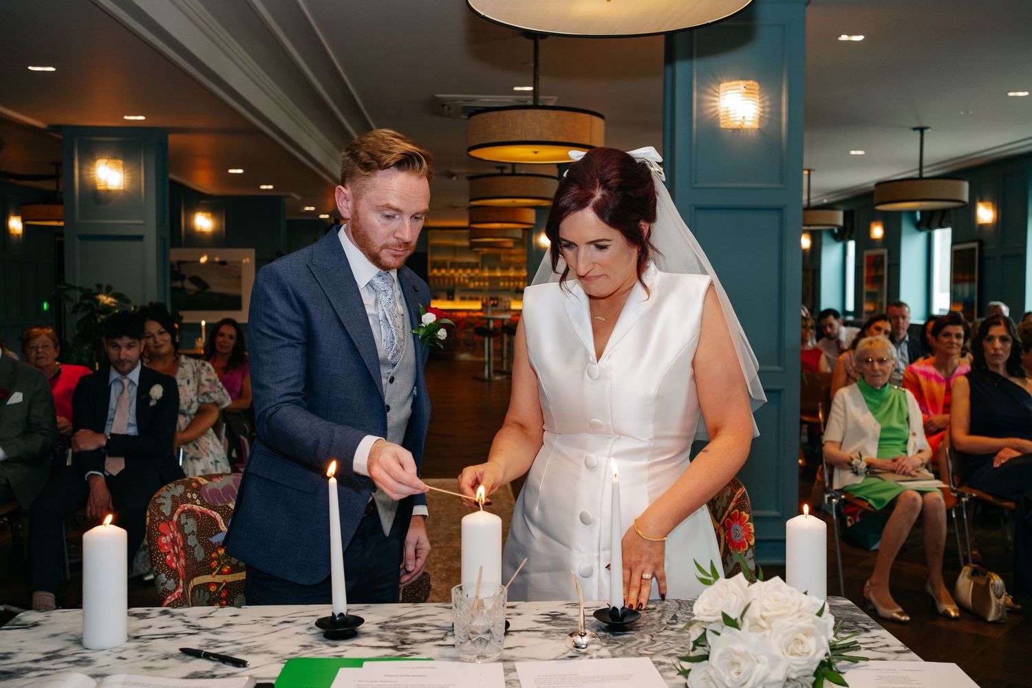 Wedding ceremony celebration with guests seated at long tables in a modern venue.