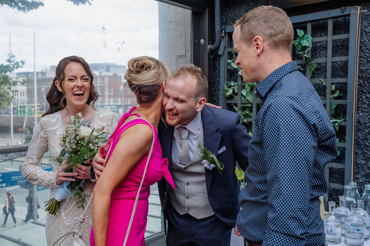 Wedding party members share laughs and conversations in a bright indoor venue.
