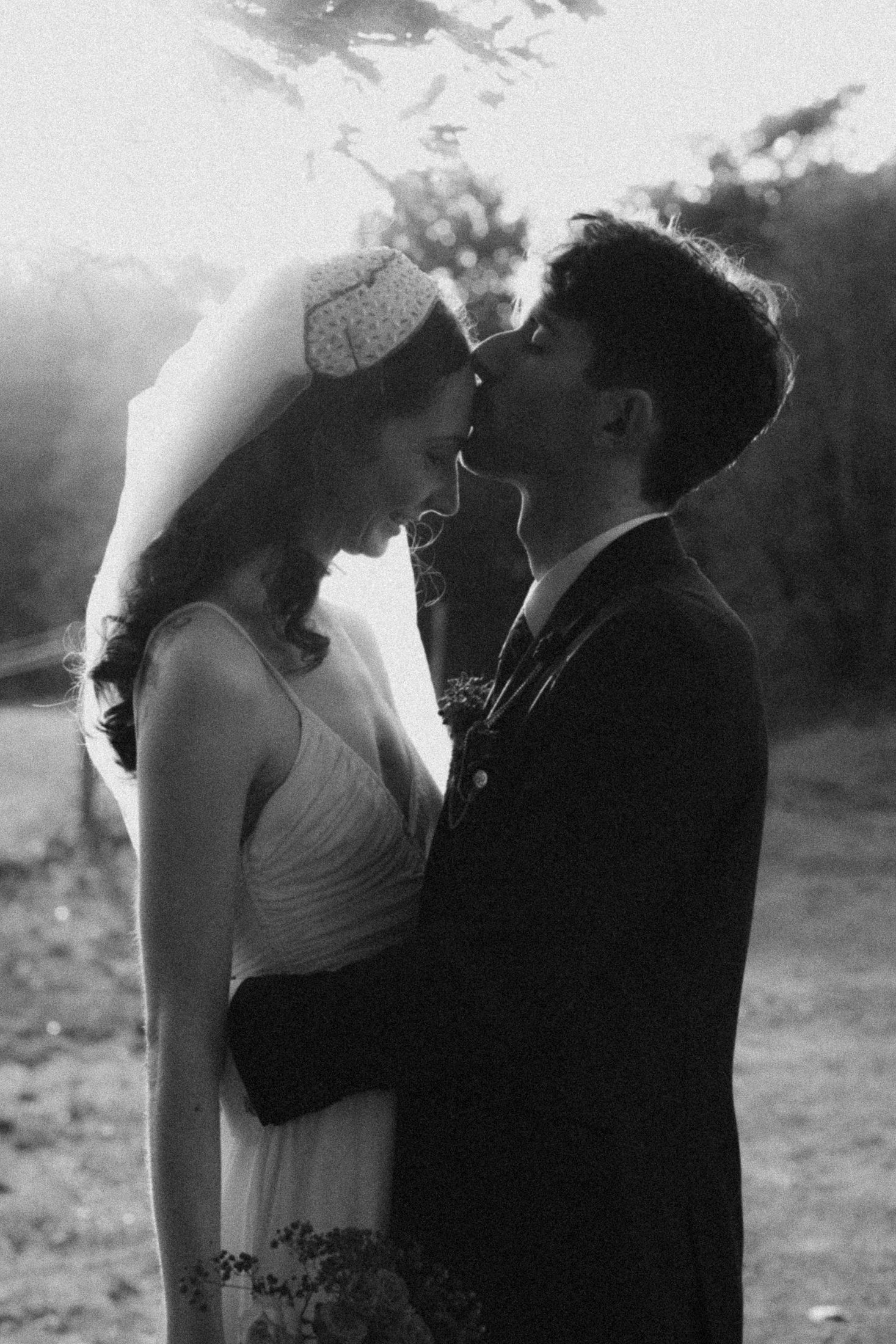 A romantic black and white wedding photo of a couple sharing an intimate moment at sunset.