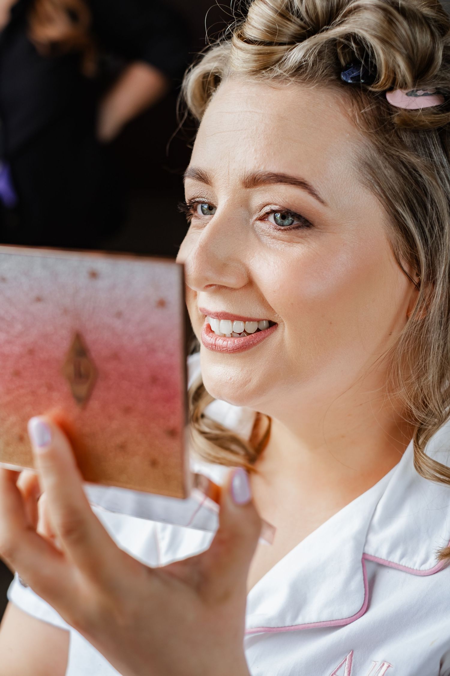 Close up of person with hair in rollers looking at mirror during wedding preparations.