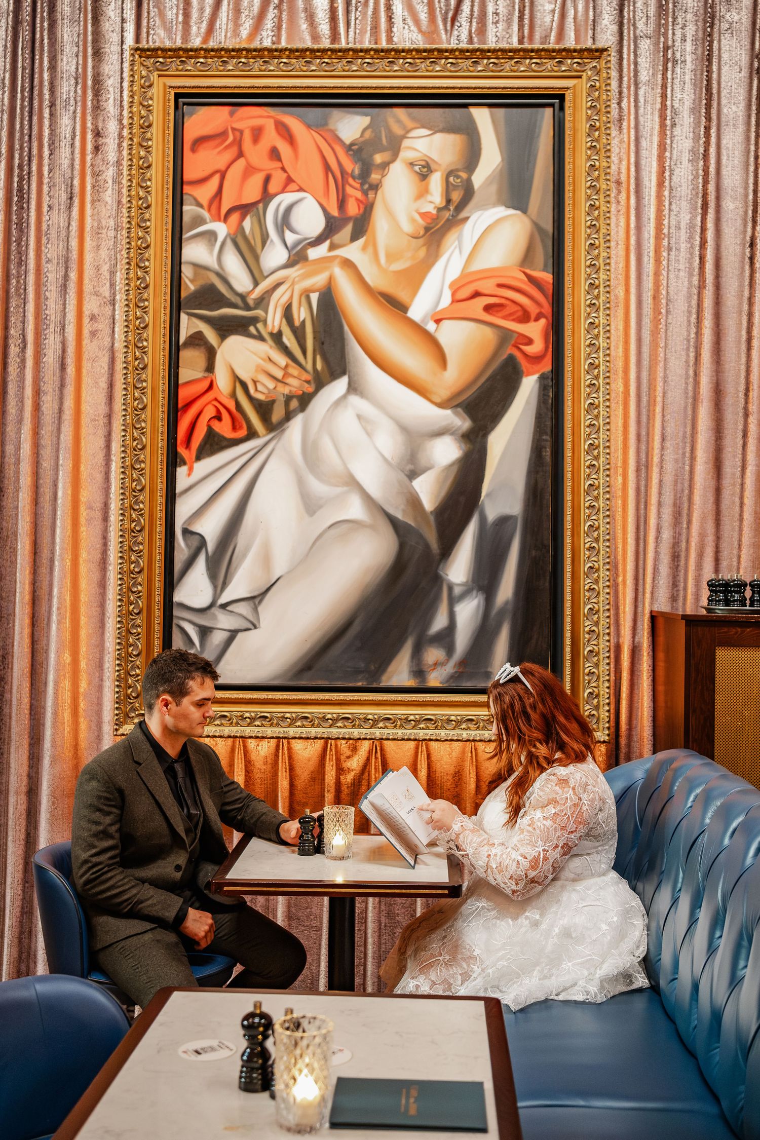 Elegant interior scene with vintage painting and blue velvet seating in sophisticated setting.