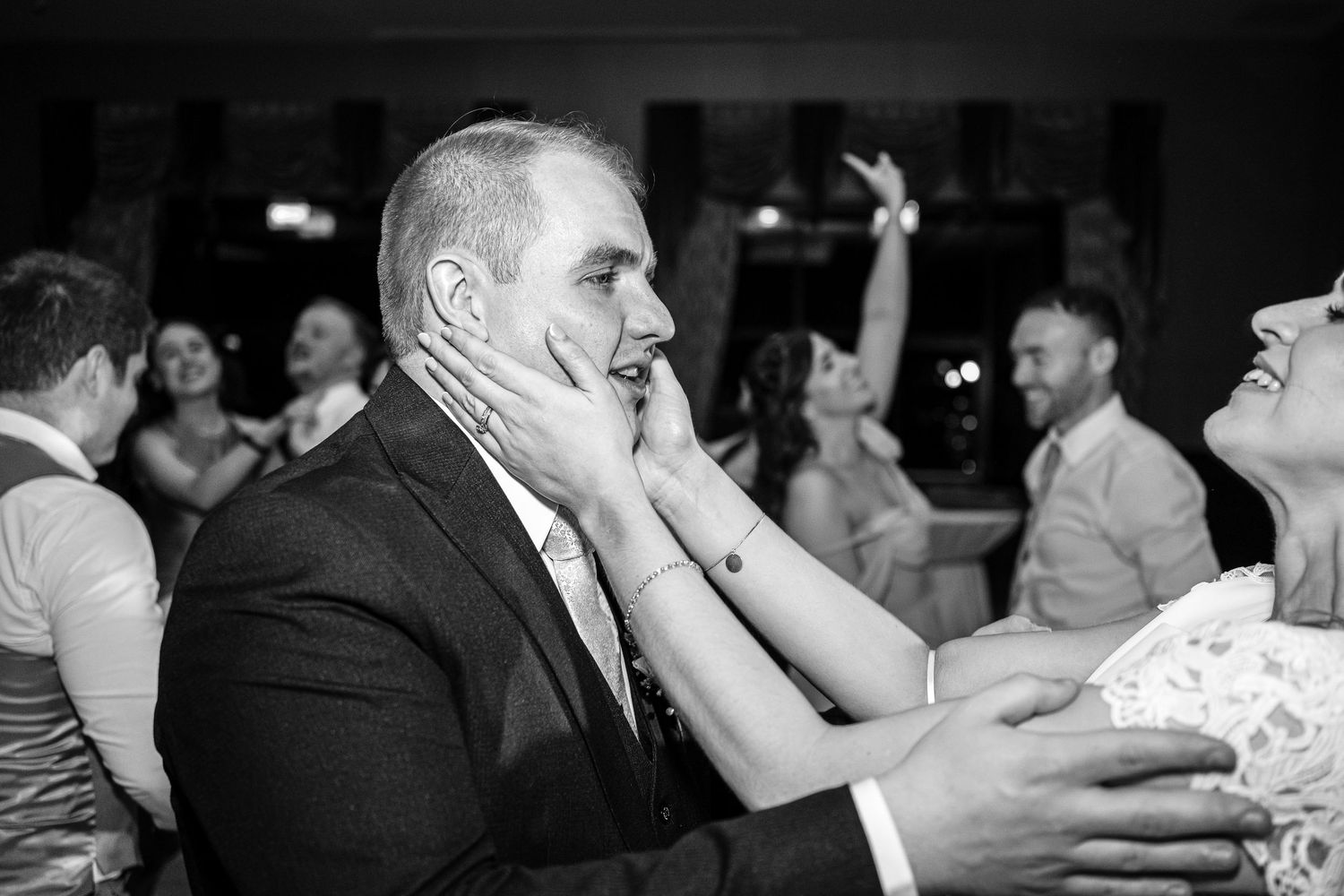 Guests dancing and celebrating at a dimly lit wedding reception venue.