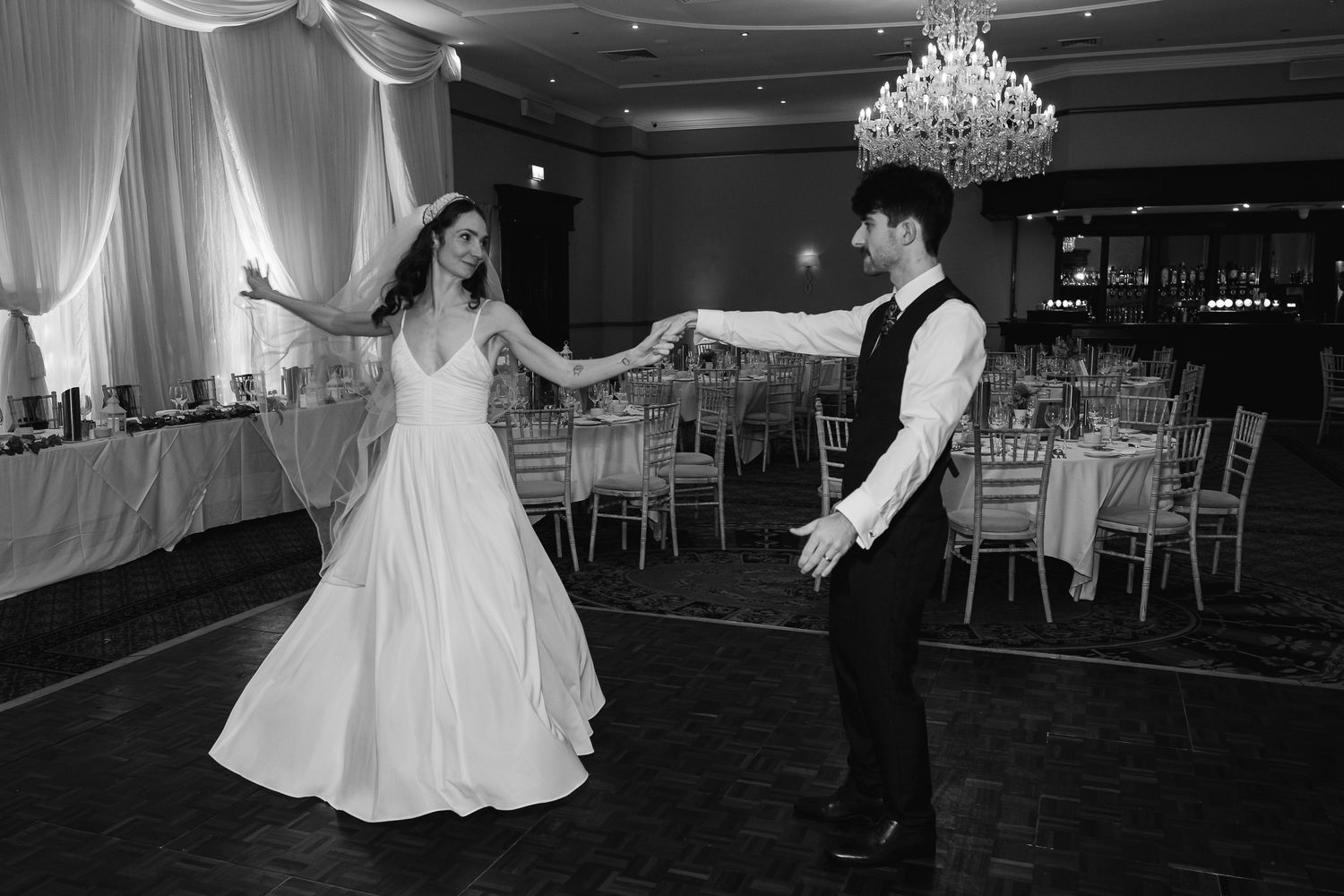 Wedding reception dance floor with elegant chandelier lighting and guests dancing.