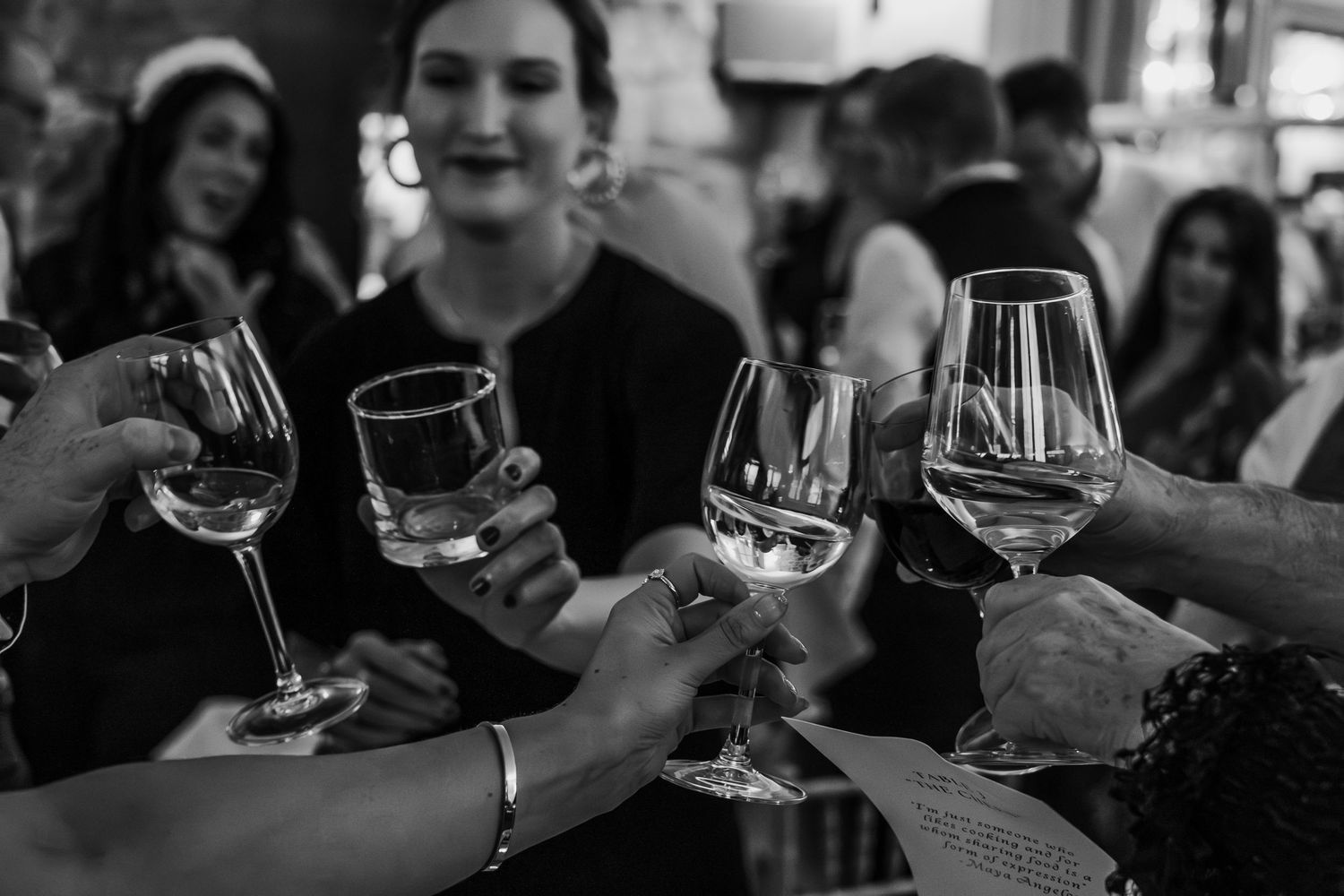 Black and white photo of wedding guests clinking wine glasses in a celebratory toast.