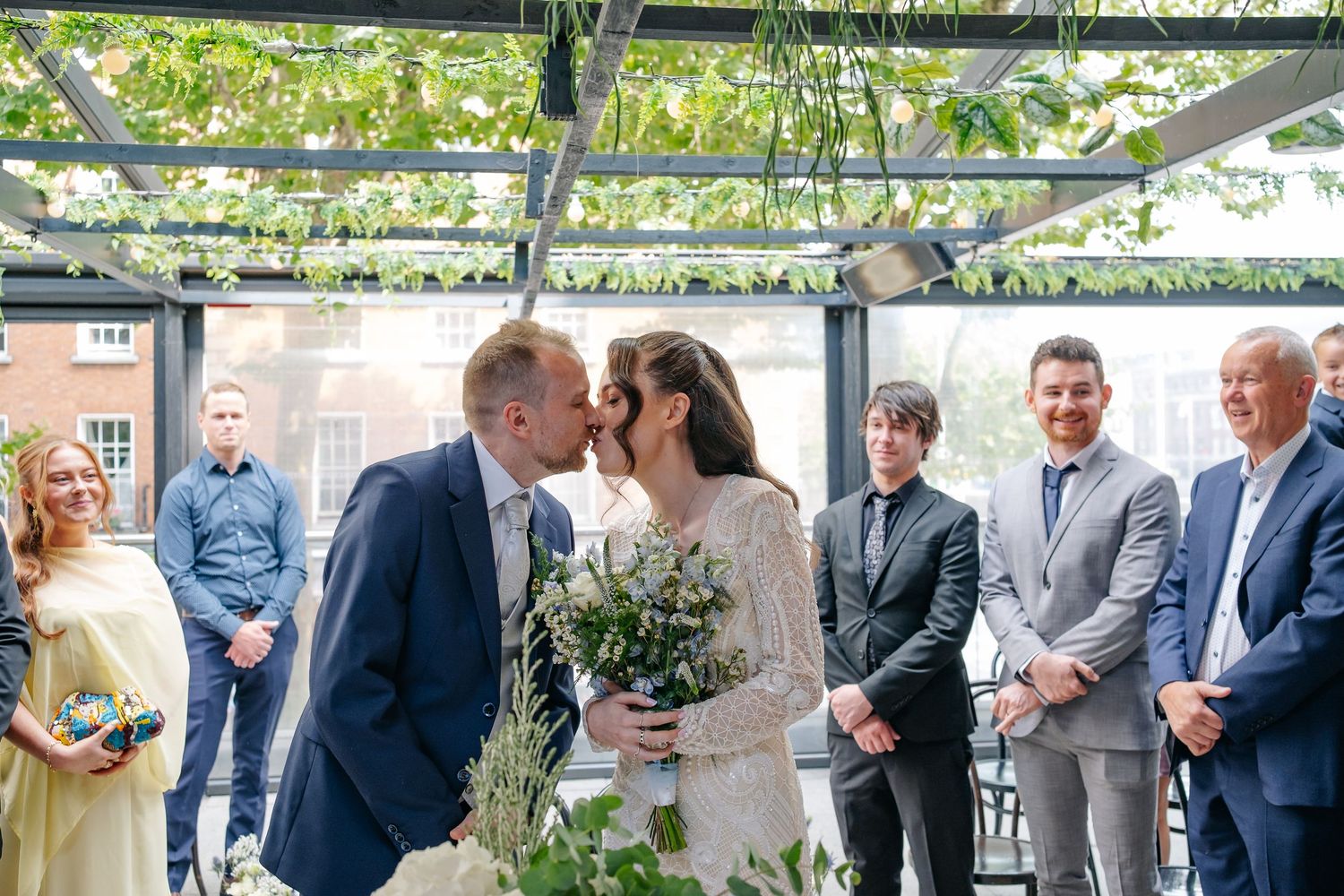 Wedding guests mingling outdoors under a white tent during a reception.