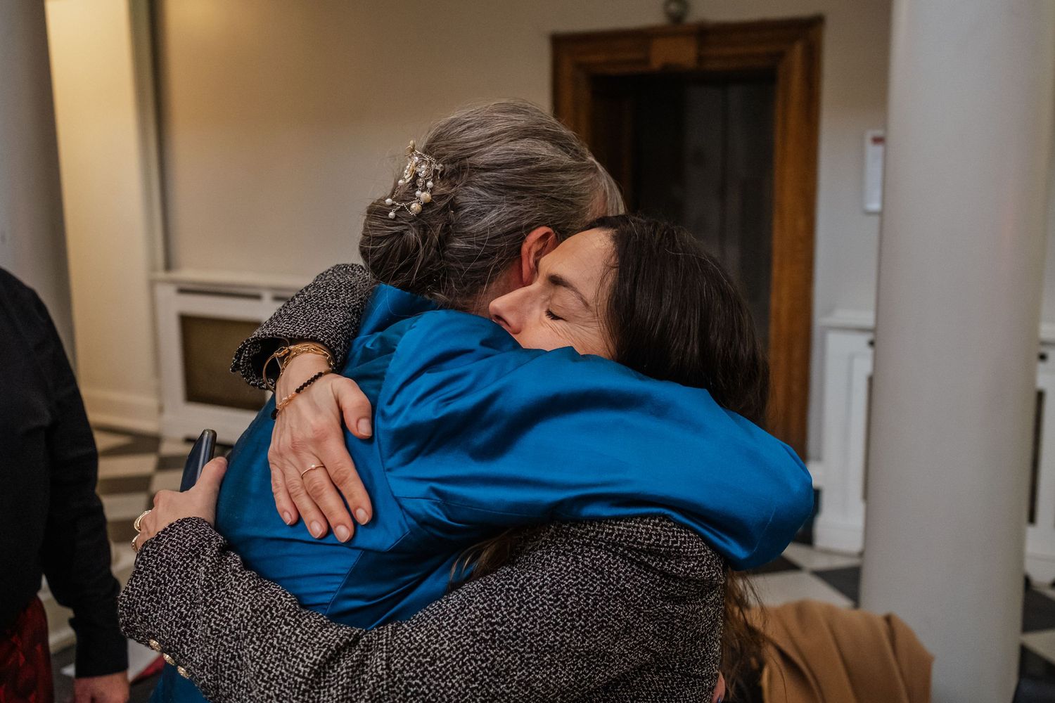 Two people sharing an emotional embrace in a hallway.