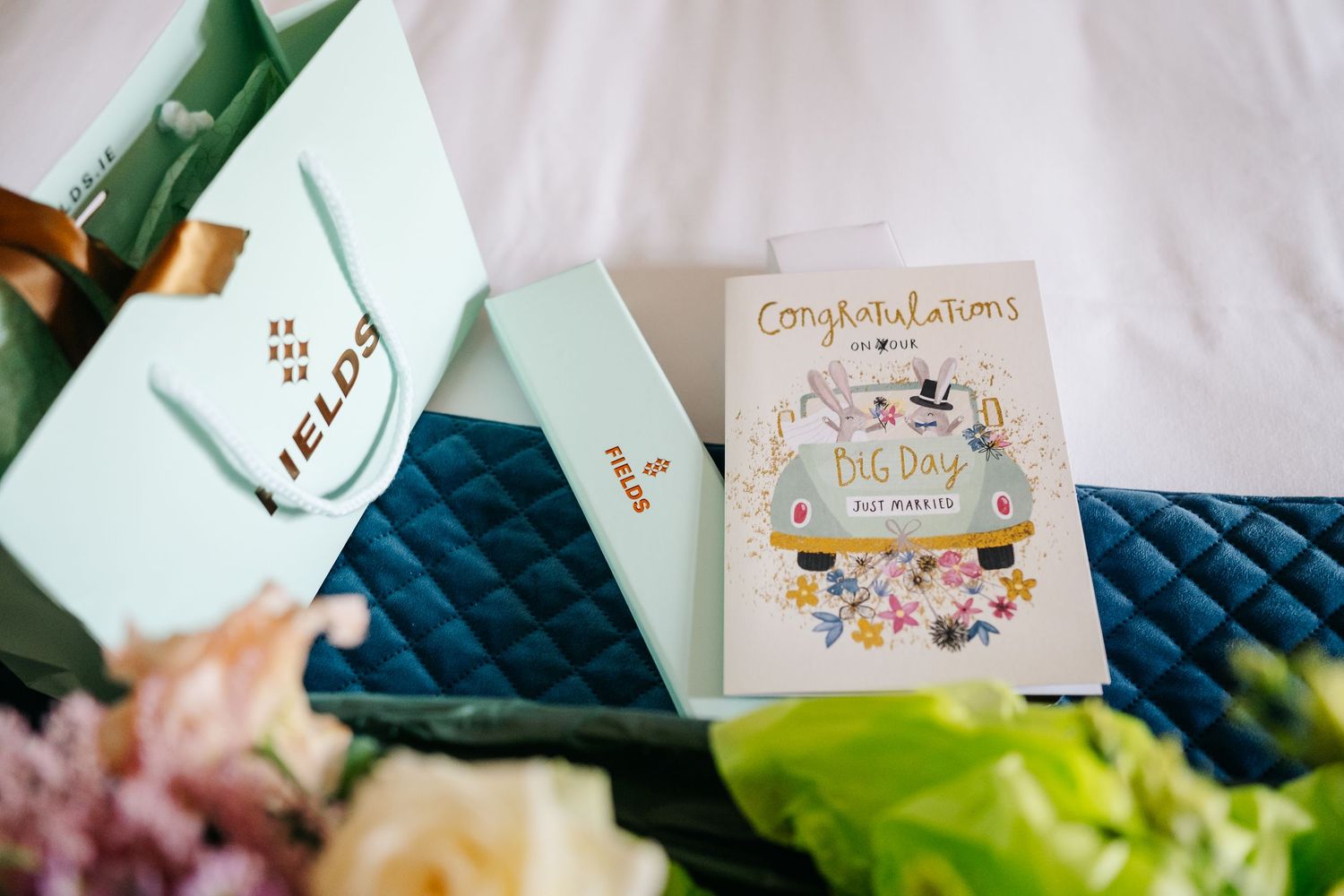 A wedding table setting features scattered floral arrangements, congratulatory cards, and elegant decor details in muted colors.
