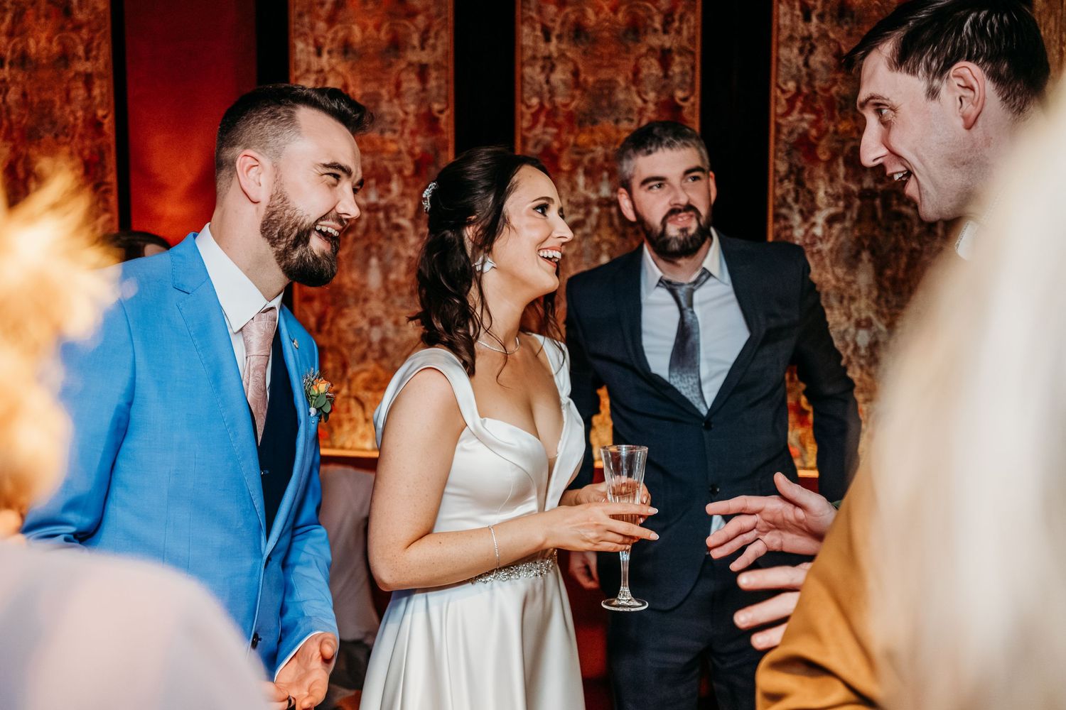 Wedding guests enjoying conversation and champagne at an elegant indoor reception.