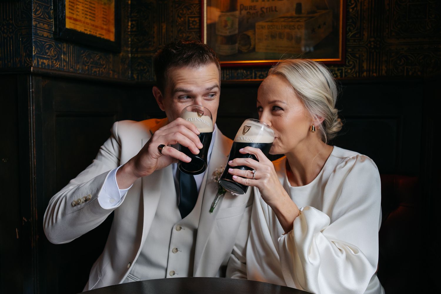 Bride and groom sharing Guinness pints together at a pub on their wedding day.