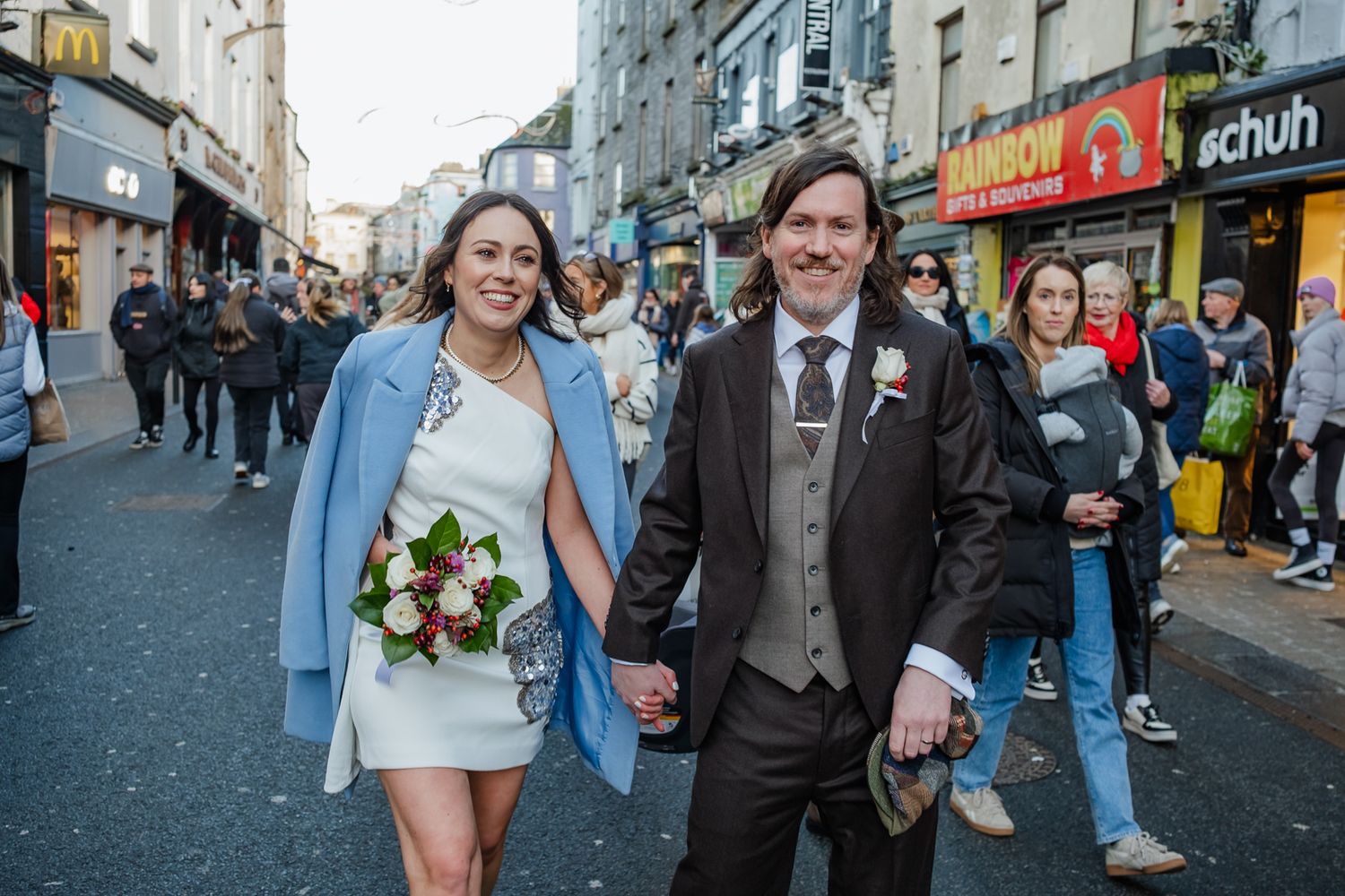 Newlyweds walking through city streets during their wedding celebration.