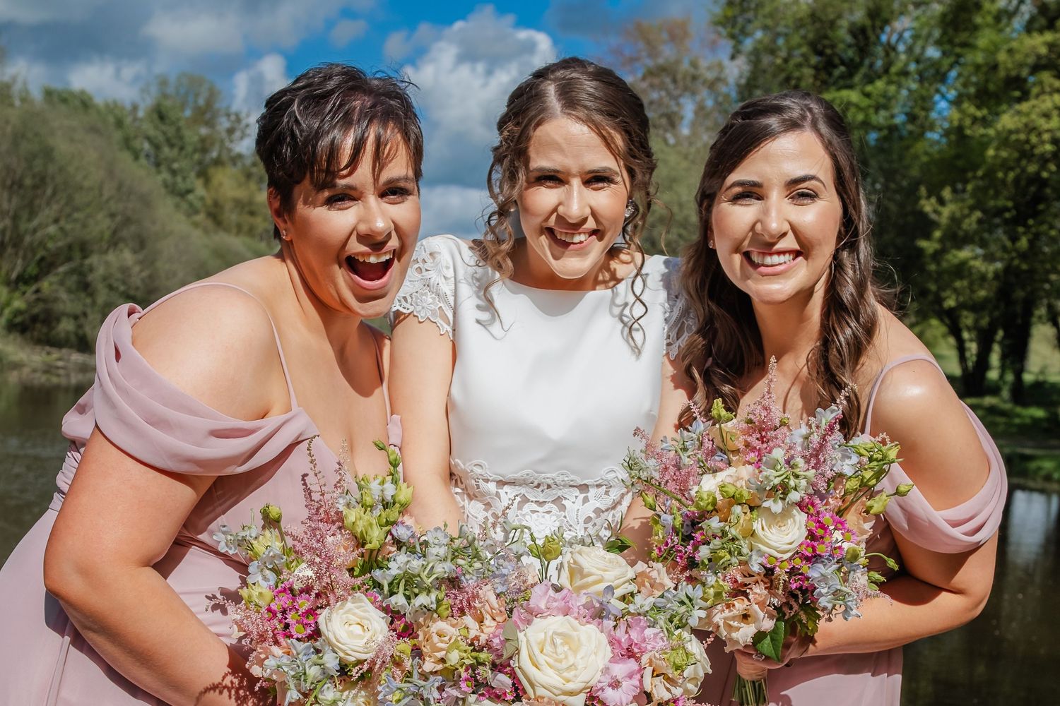 People sharing joyful moments and laughter during an outdoor celebration with floral bouquets.