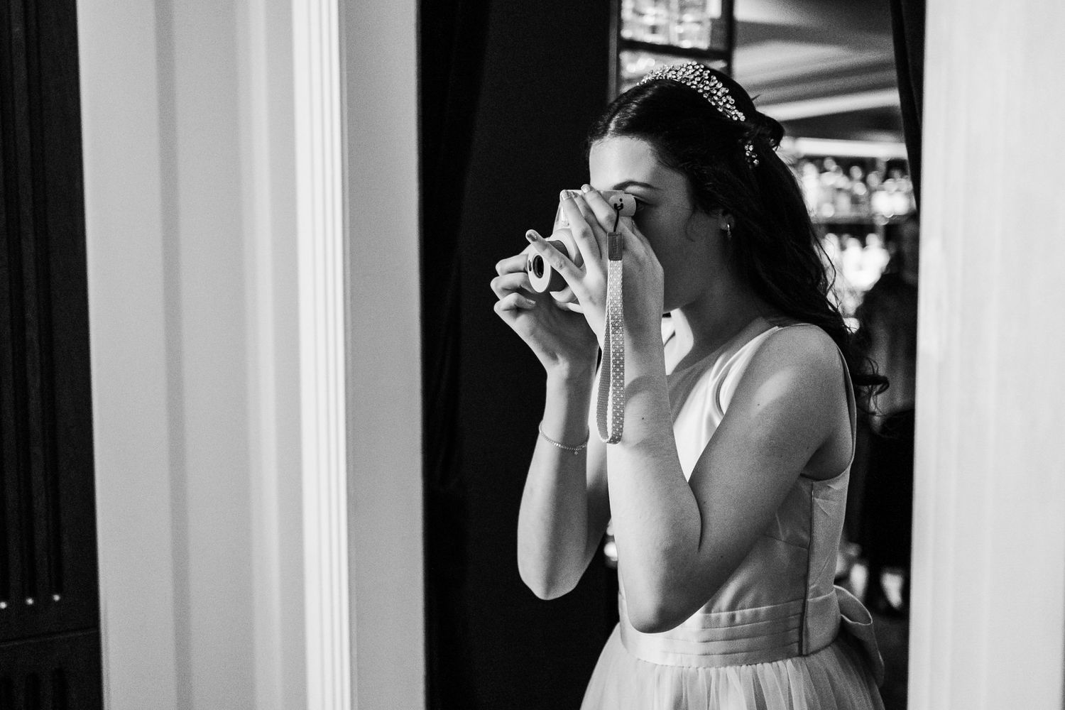 A bride taking a photo with a vintage camera in black and white.