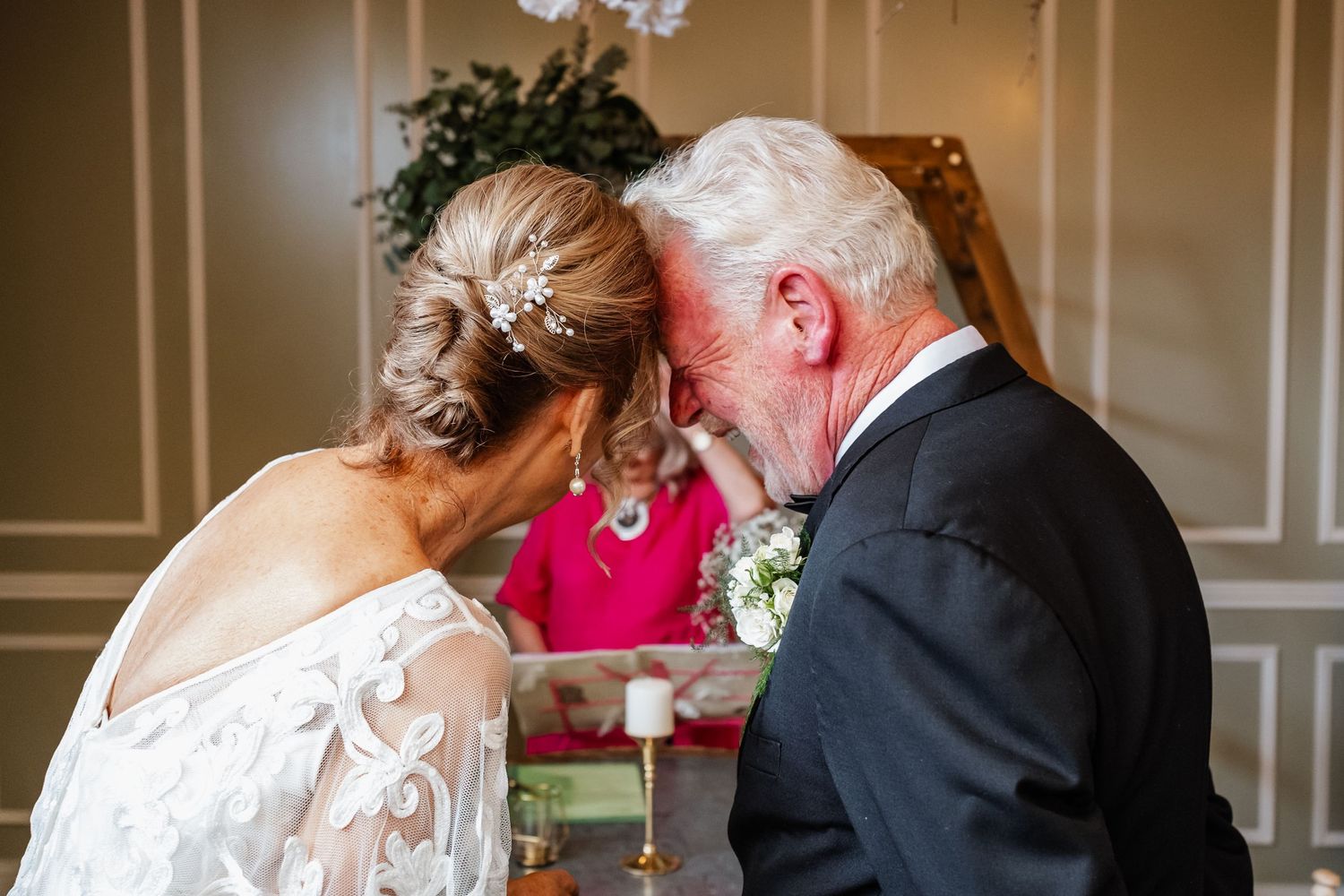 Joyful embraces shared among wedding guests against stone wall backdrop.