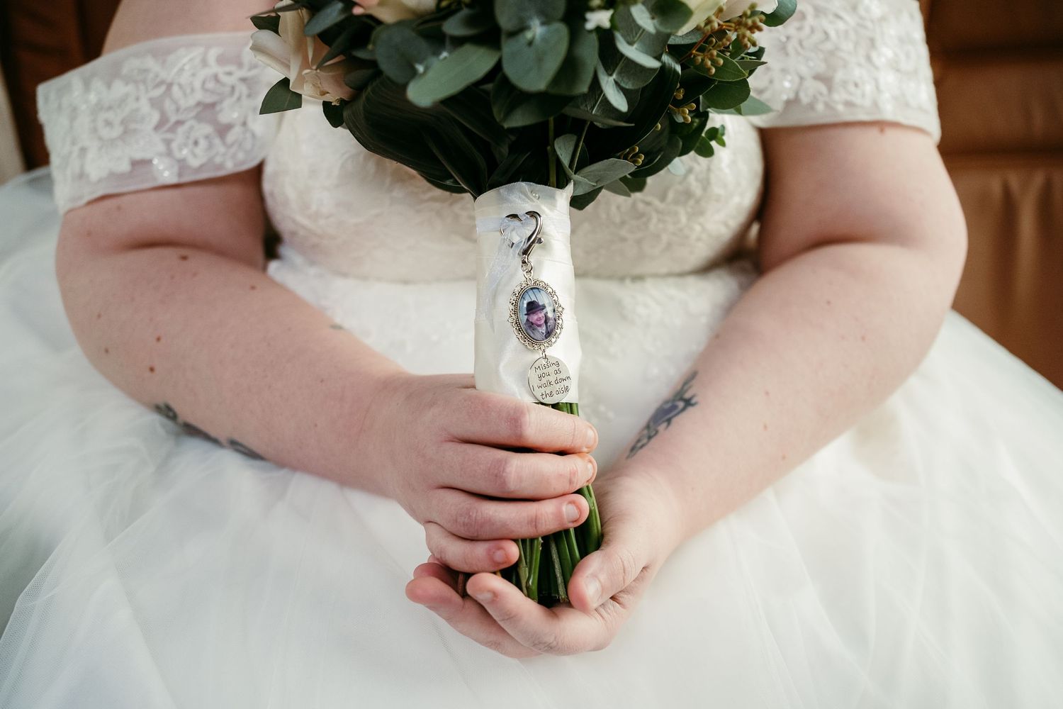 Close-up of bridal bouquet with sentimental charm attachment.