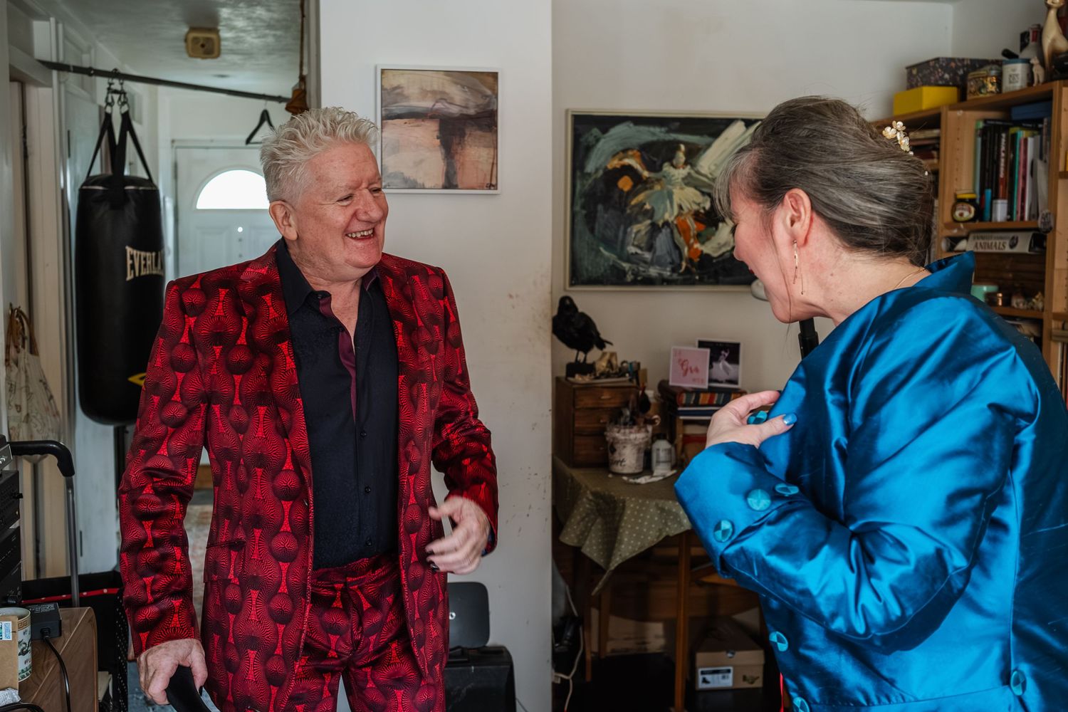 Two people in vibrant formal attire conversing in a casual indoor setting.
