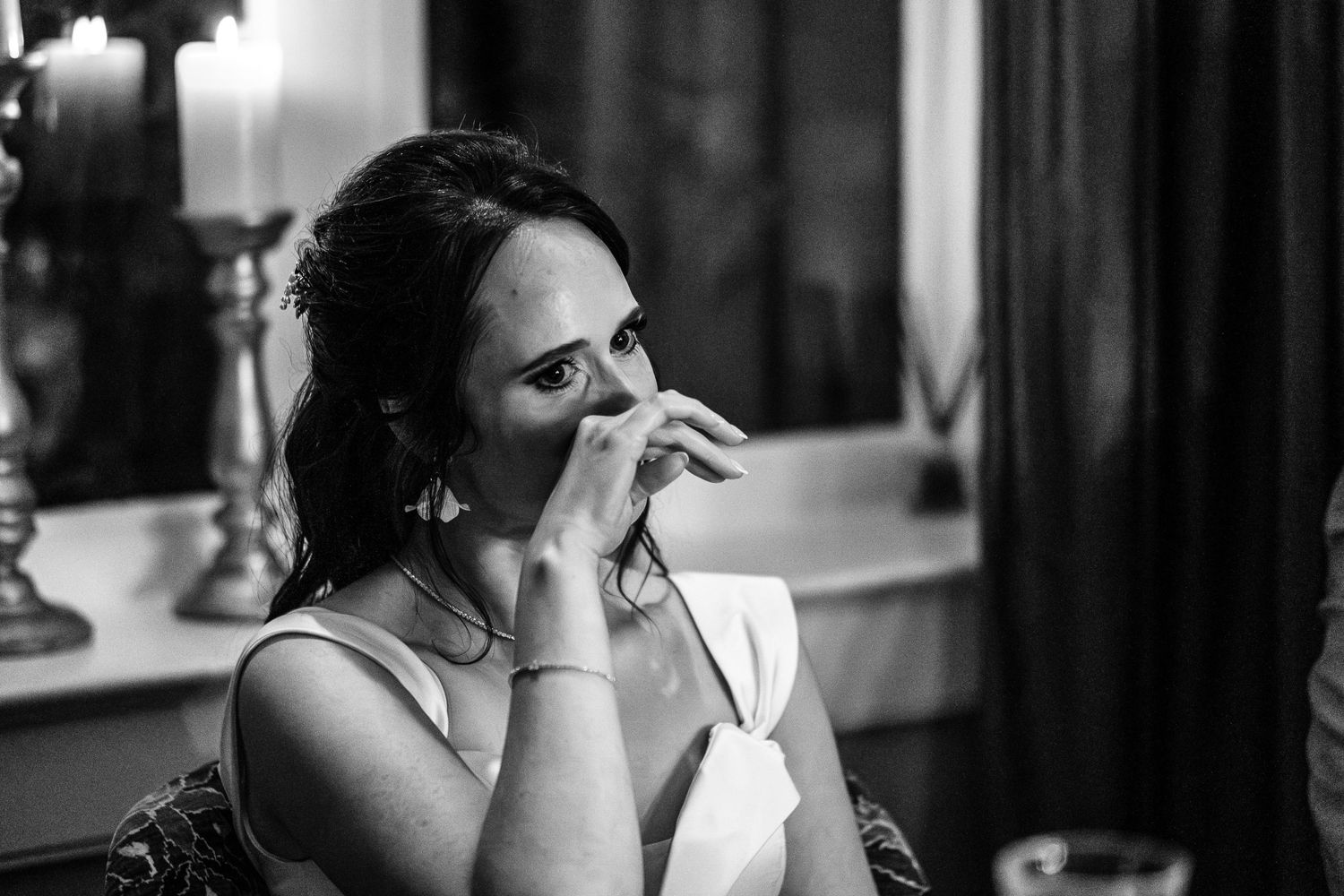 An emotional black and white moment captures a bride's genuine reaction during wedding festivities.