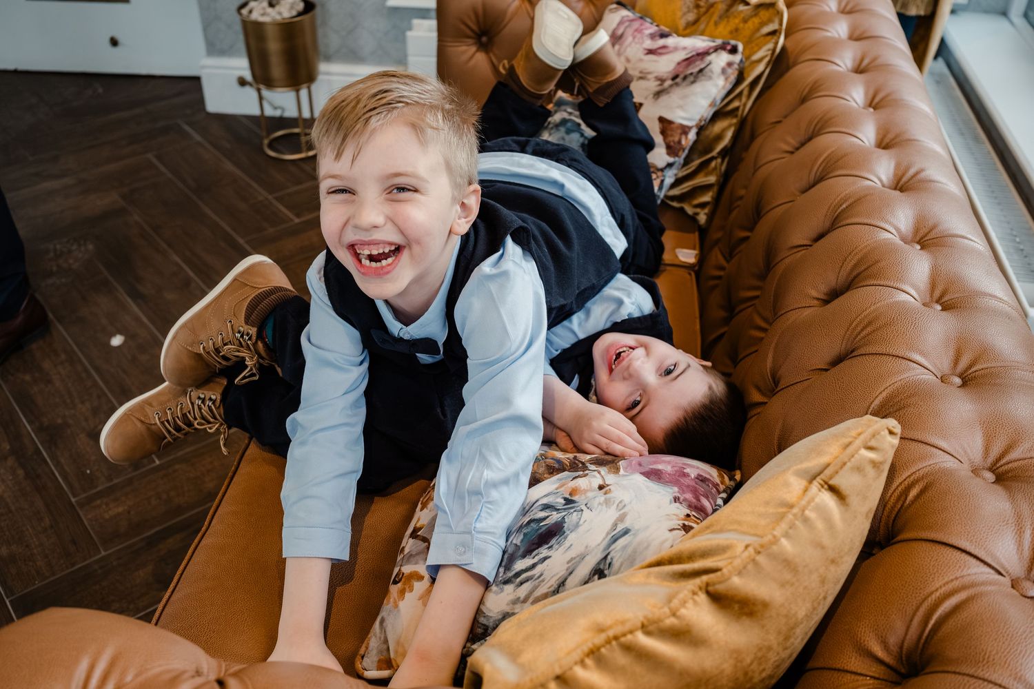 Playful moment captured on a brown leather couch during formal event preparations.