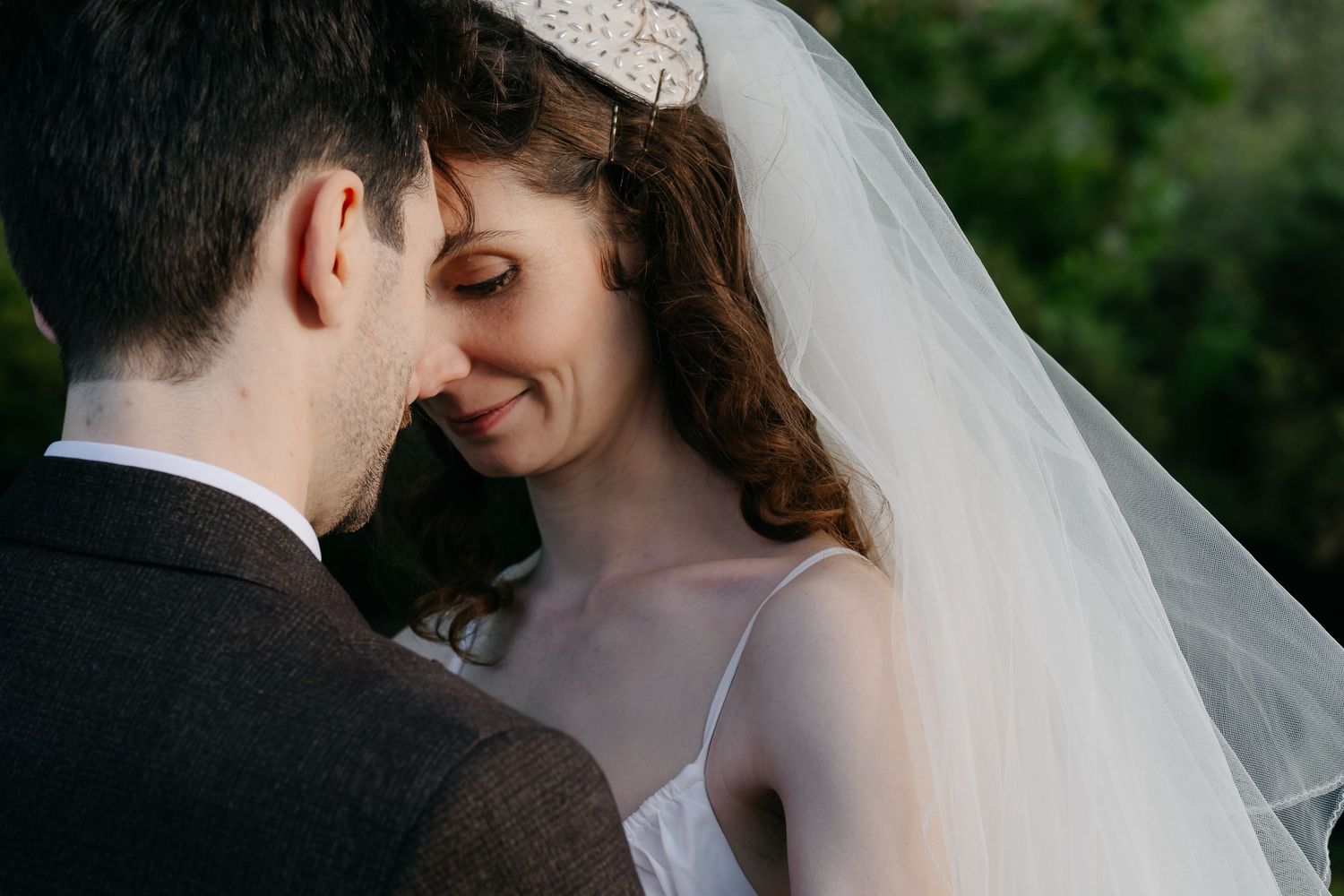 Romantic outdoor wedding portraits with couple embracing in garden setting.