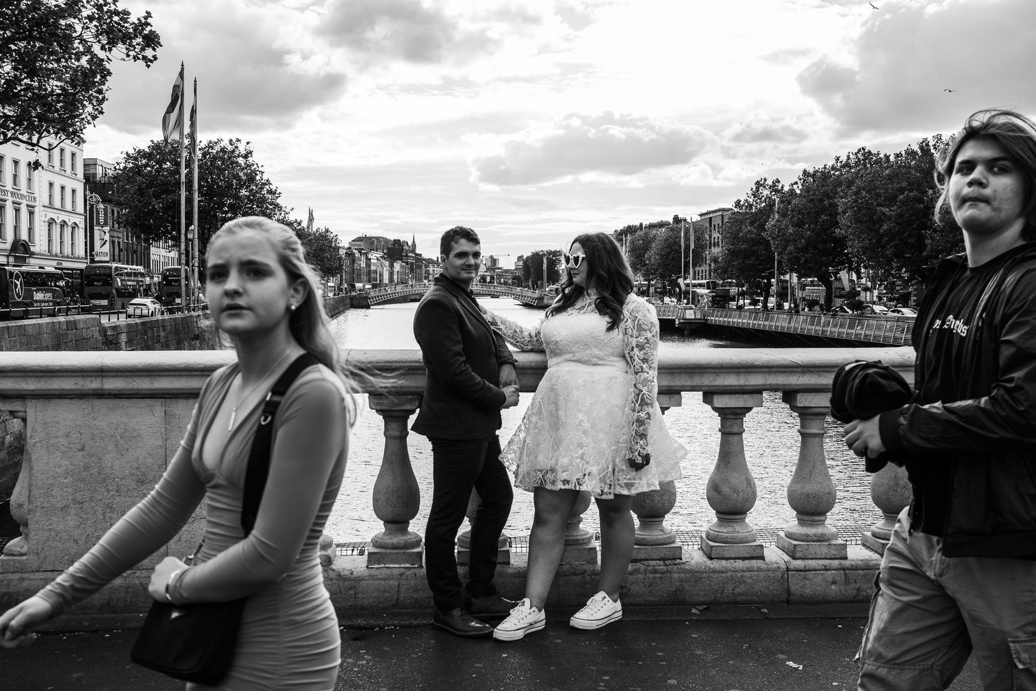 People gathering on a historic stone bridge in Dublin's city center on a cloudy day.