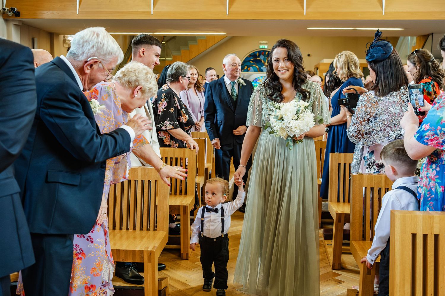 Wedding ceremony in wooden church hall with guests seated in rows.