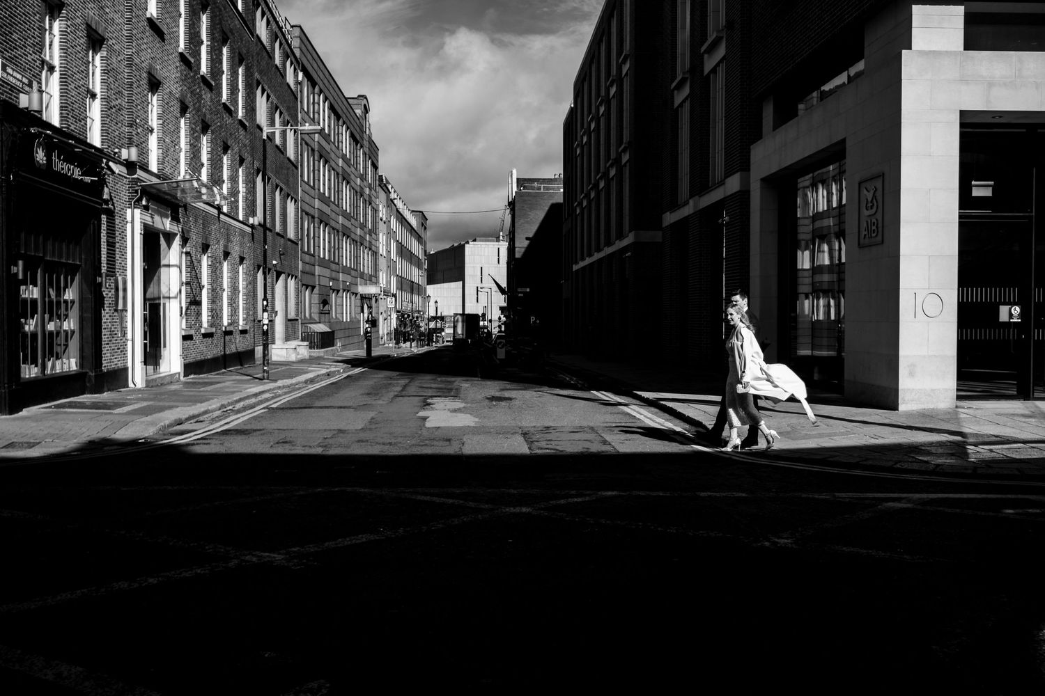 Black and white urban street scene with dramatic shadows and historic buildings.