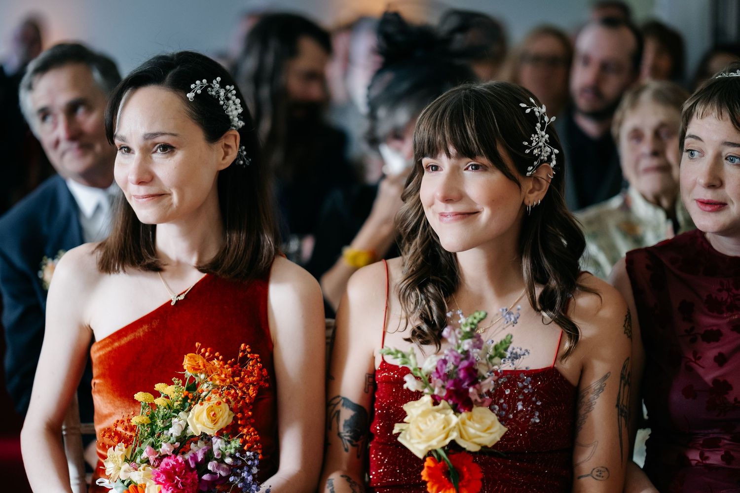 Wedding party attendees wearing colorful dresses and holding vibrant floral bouquets at a formal celebration.