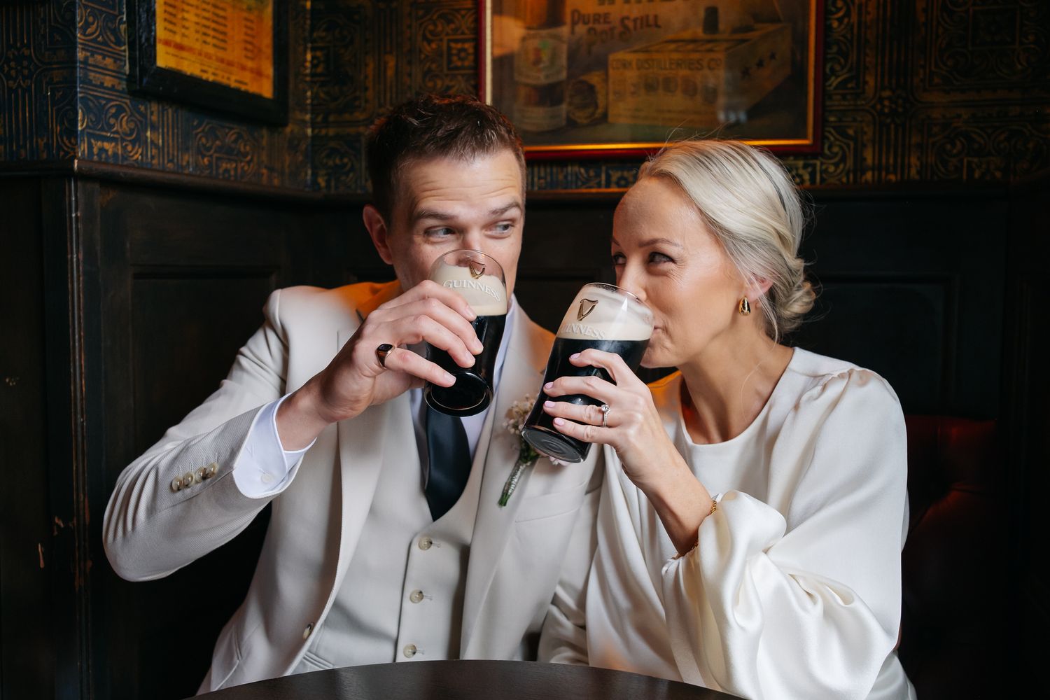 Bride and groom sharing Guinness beers together at a pub on their wedding day.
