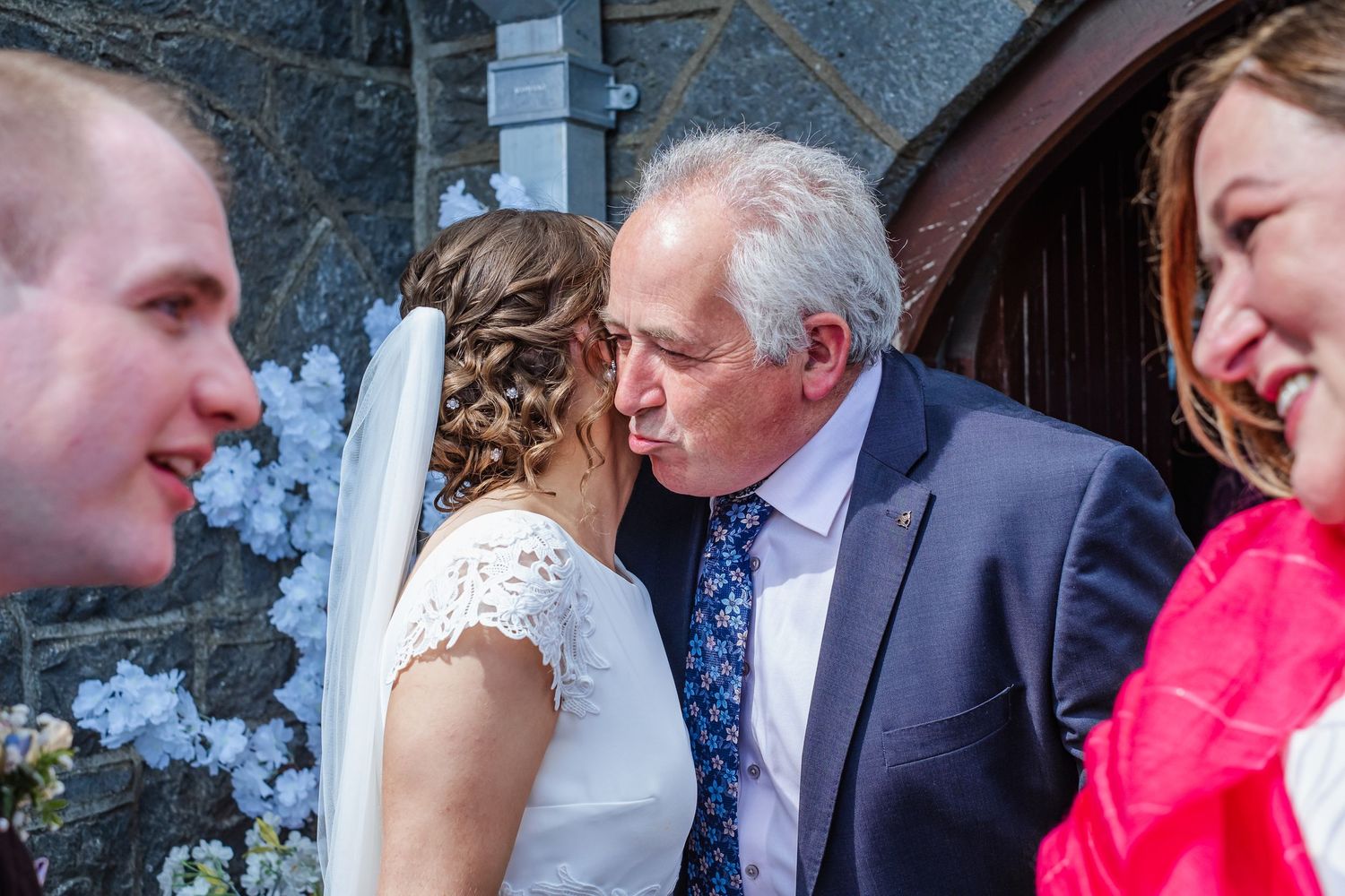Wedding guests and family members sharing embraces and happy moments during an outdoor celebration.