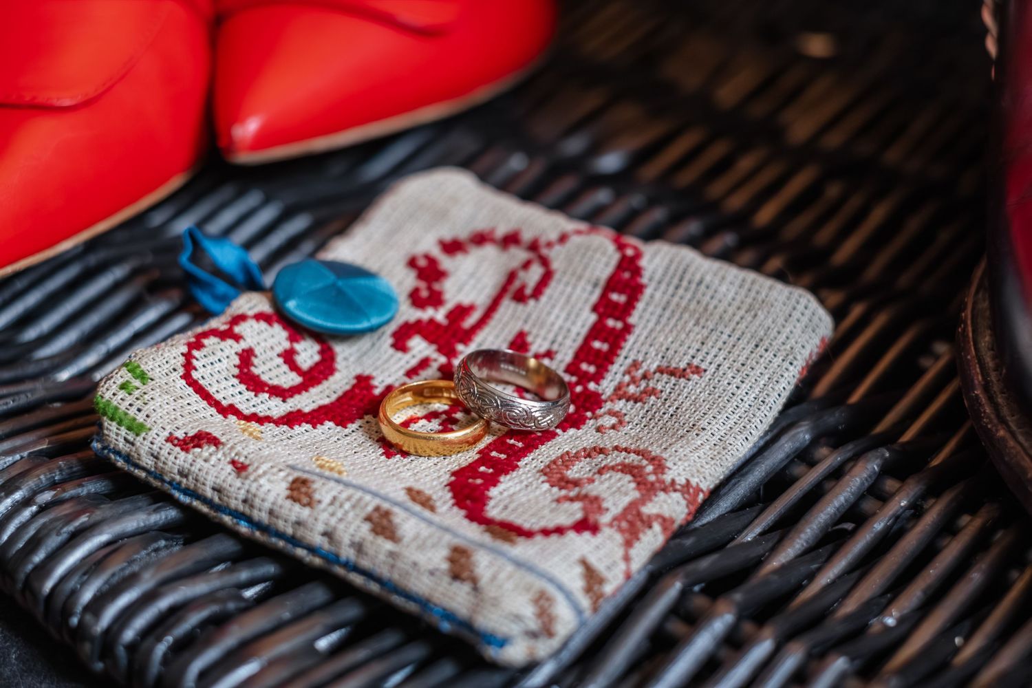 Red embroidered pattern on a light colored fabric with a blue accent detail.