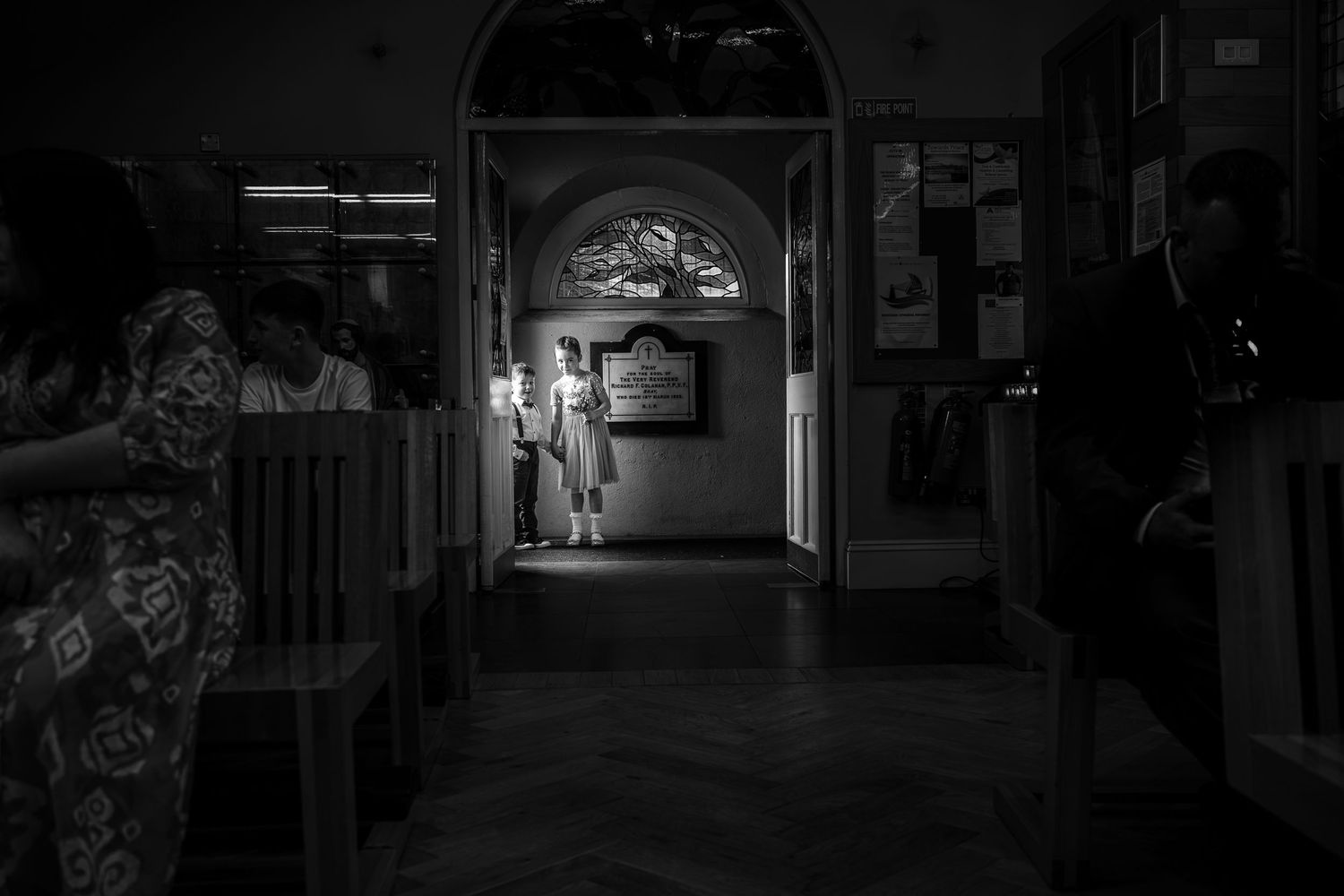 Black and white image of illuminated hallway with arched doorway.